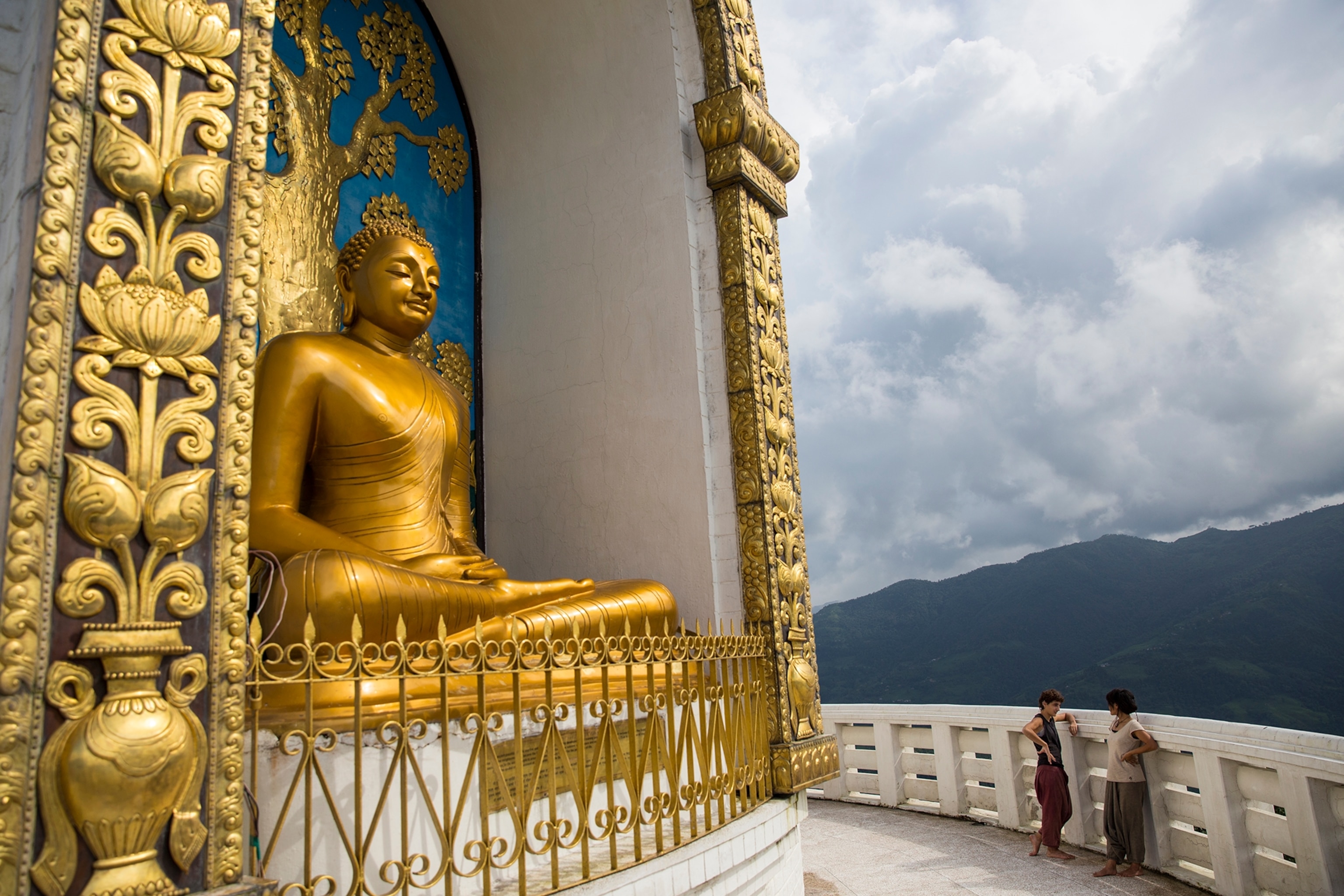 tourists standing near a Buddha statue at the Pokhara Shanti Stupa in Pokhara, Nepal