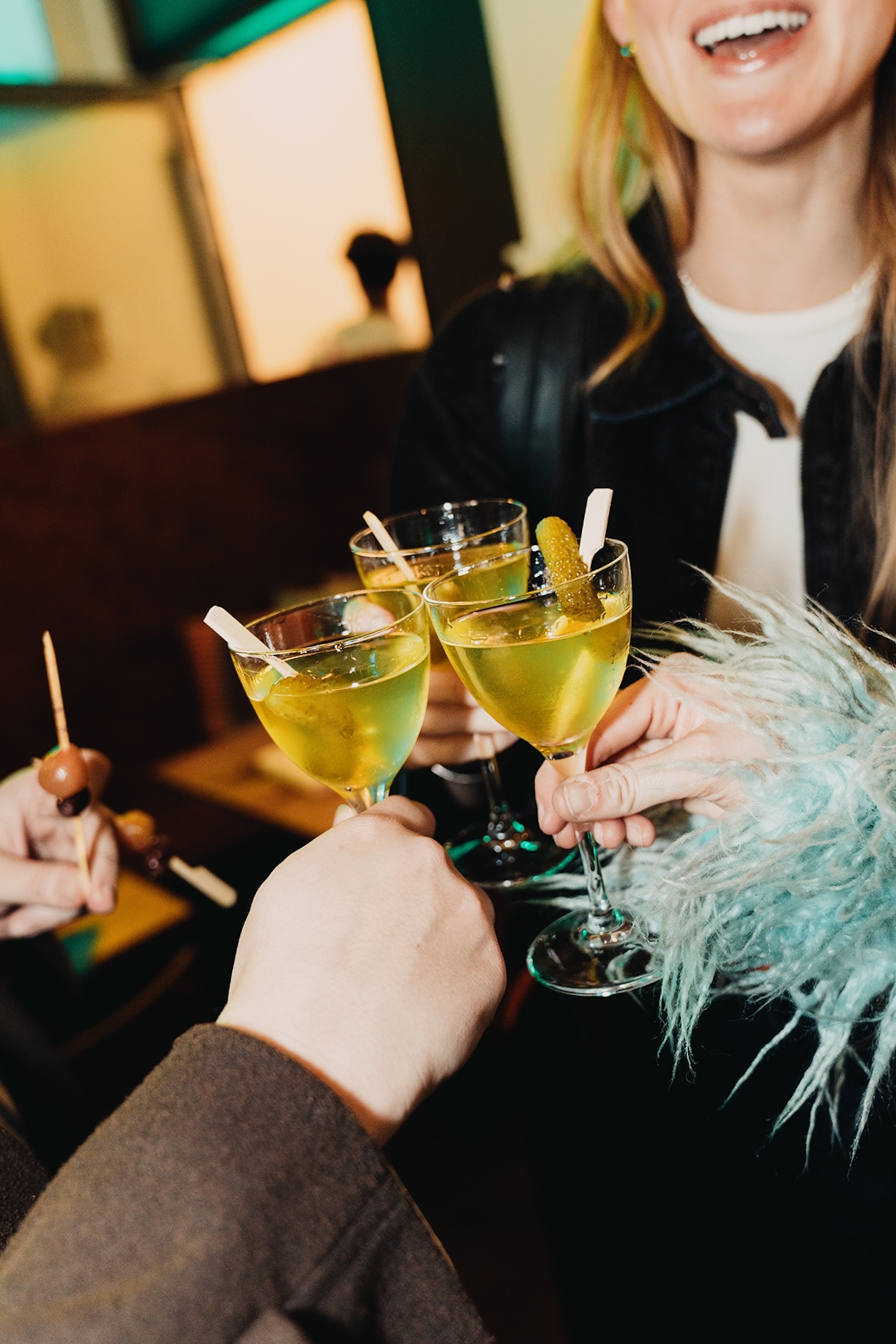People toast glasses of pickle-themed drinks.