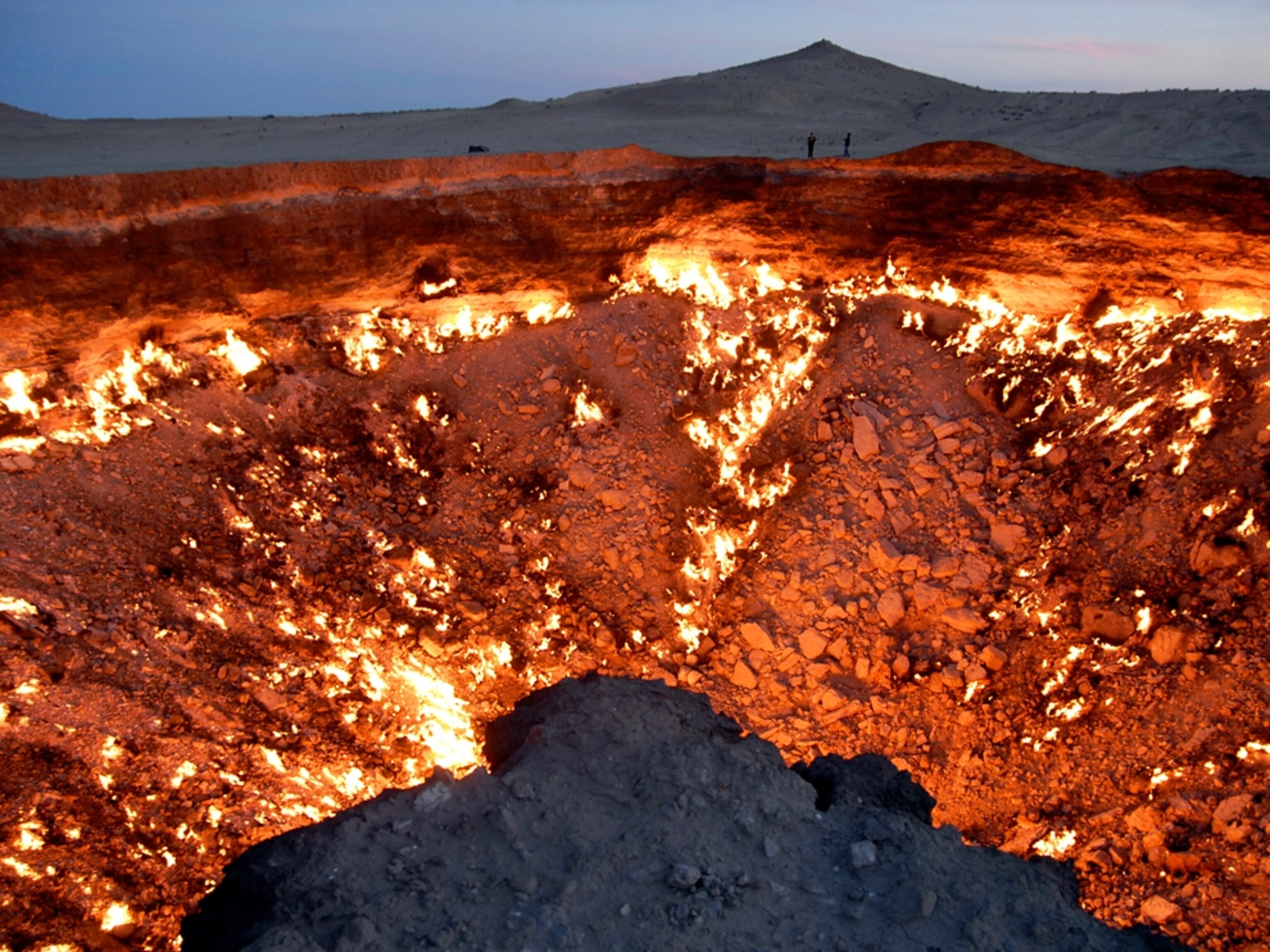 Picture people standing near the Darvaza gas crater, Turkmenistan