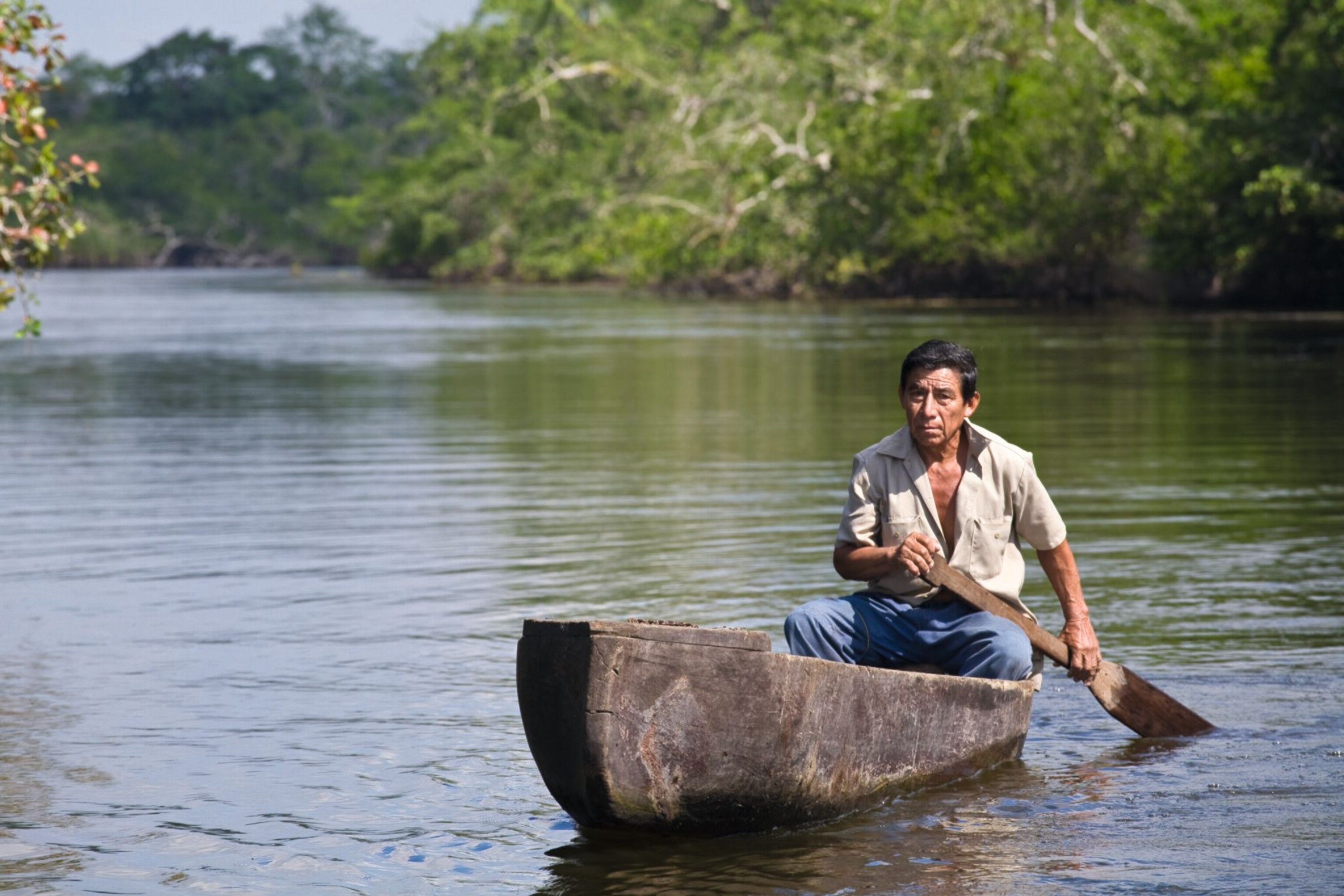 A fisherman in a traditional dugout canoe explores the waters near Lamanai.