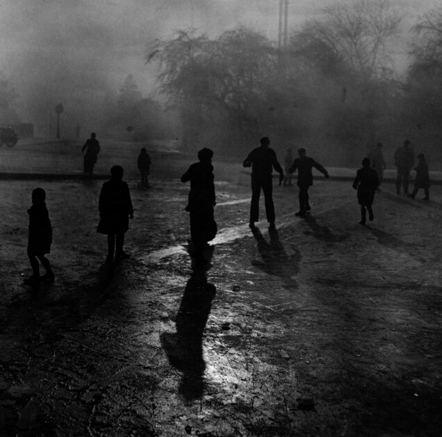Fog and ice on Hampstead Heath. Boys sliding on the ice in the fog at Hampstead Heath ponds