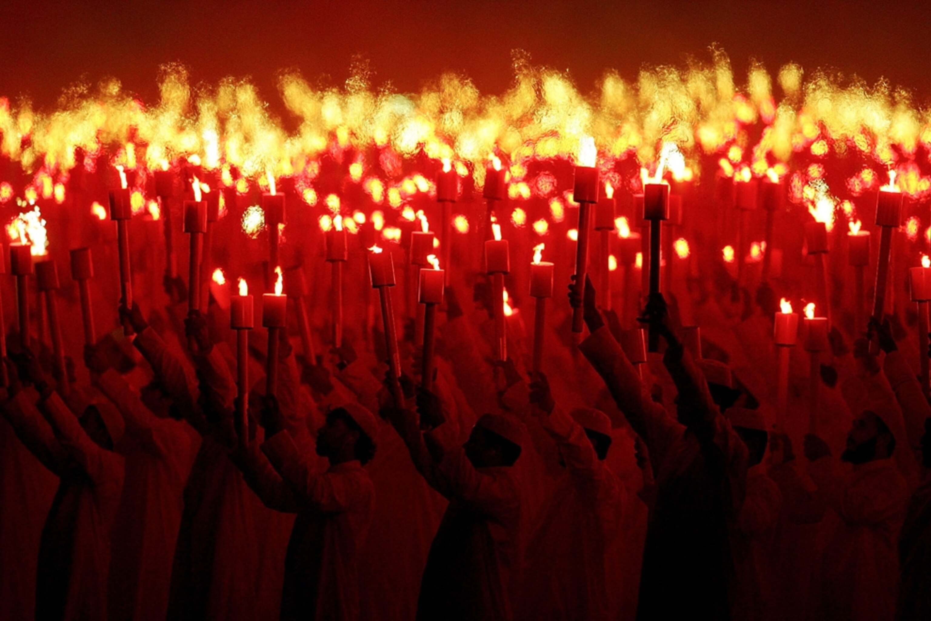 A crowd of Qataris holds torches aloft during opening ceremonies of the 2006 Asian Games picture.