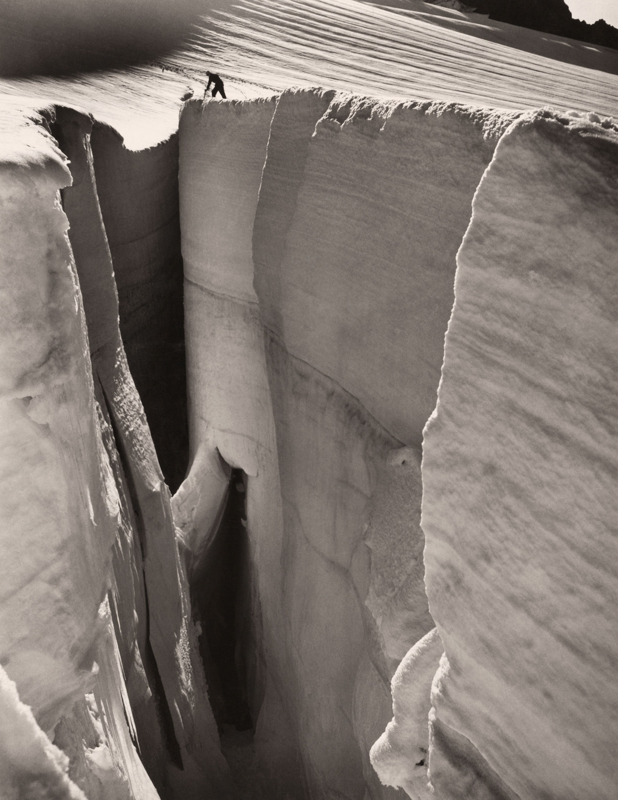 a climber peering into a crevasse on Mount Baker