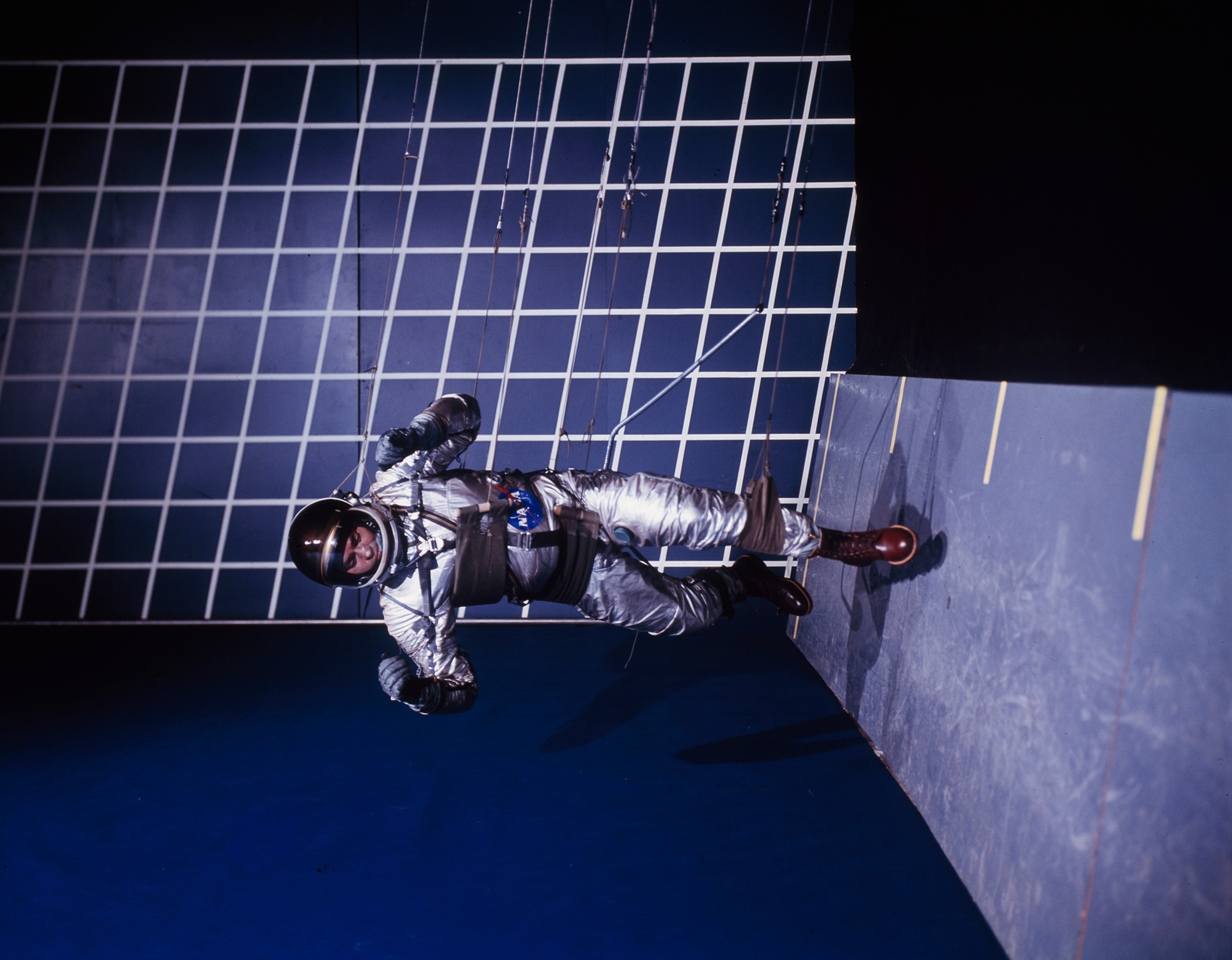 A man walks a wall in a special harness that simulates low gravity.