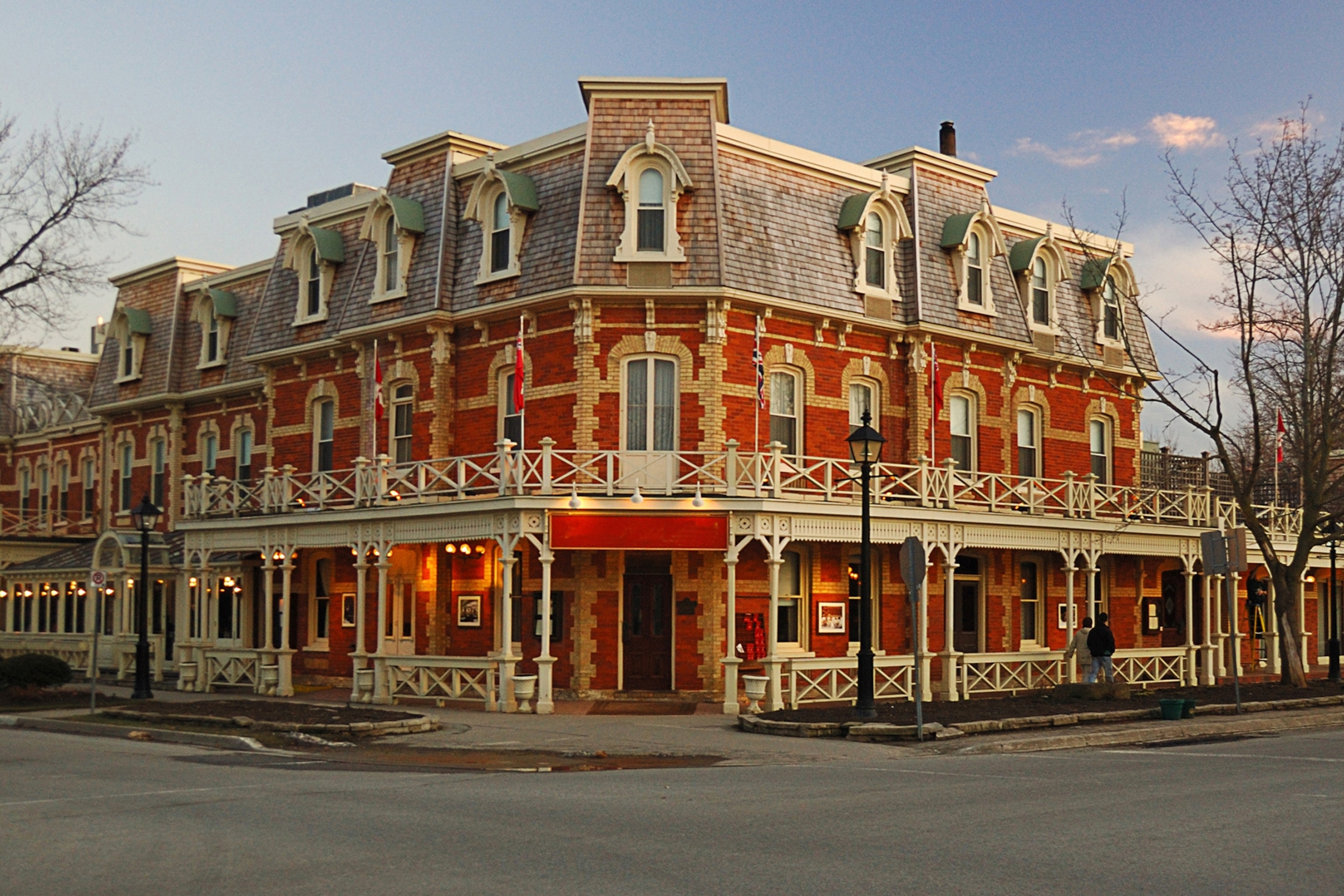 A colonial-style building with a balcony wrapping around the first floor on a quiet street.