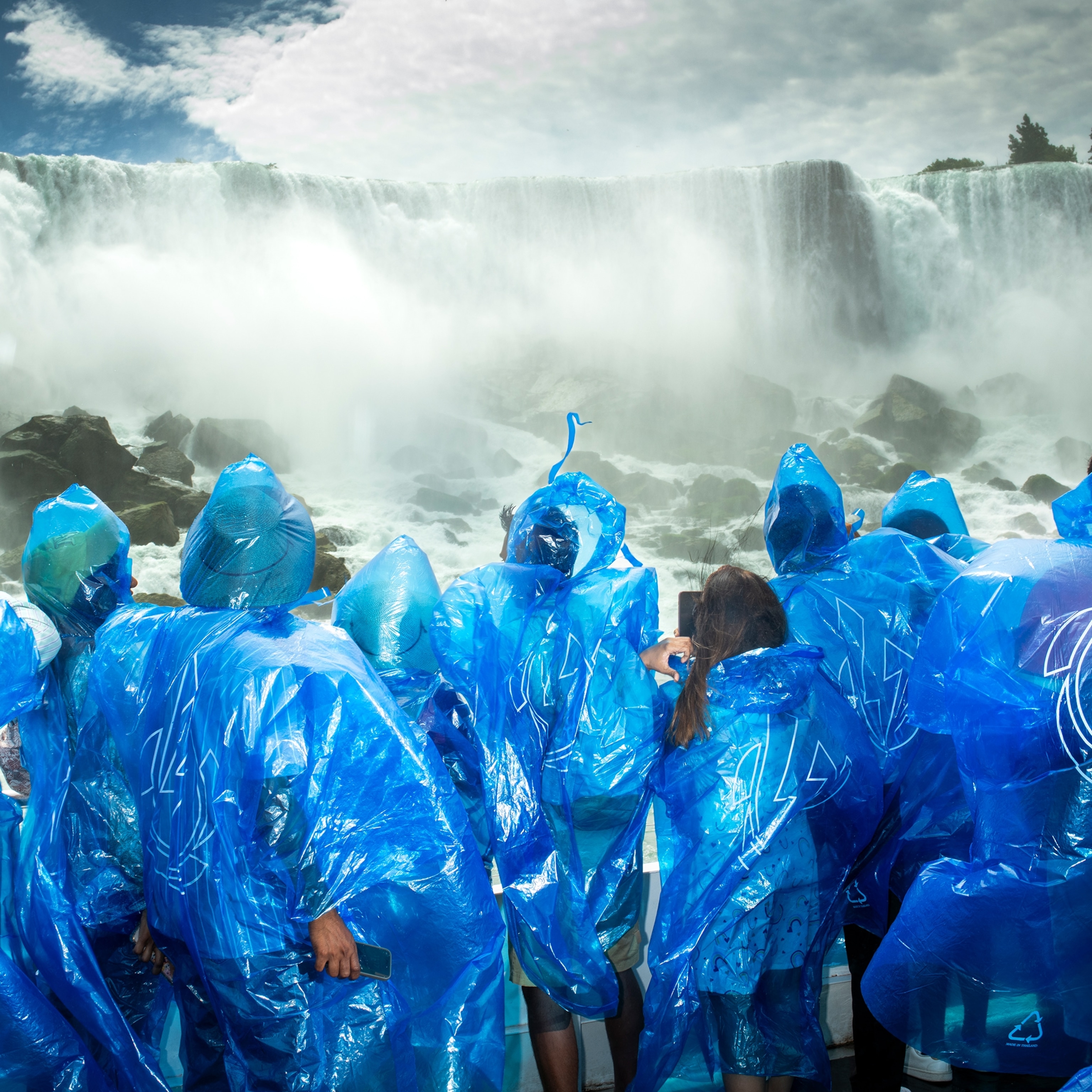 Tourists visiting the American Falls via a lower observation deck accessed after the Maid of the Mist Boat Tour, Prospect Point, Niagara Falls, NY, USA.