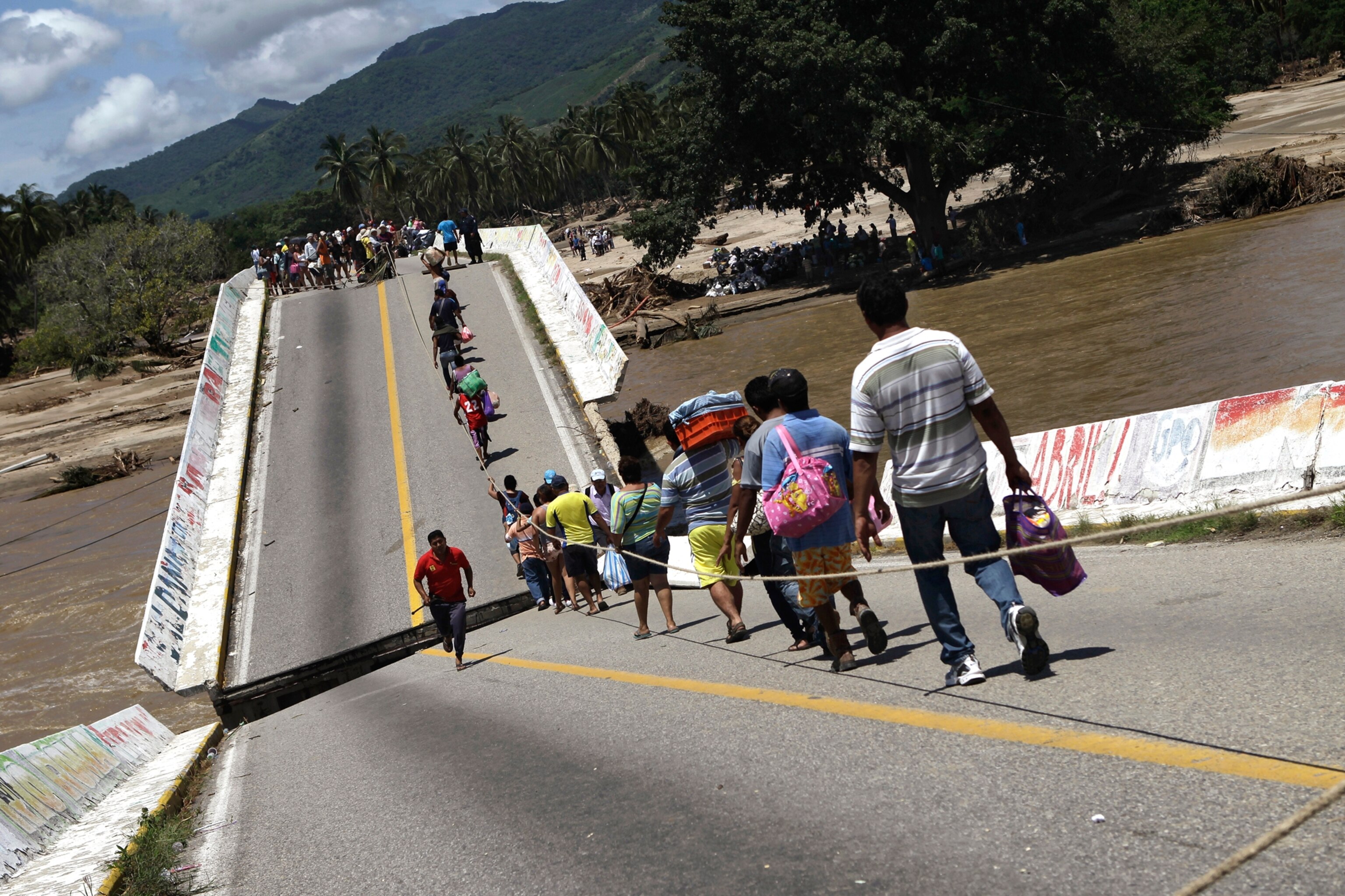 Villagers cross a collapsed bridge in Coyuca de Benitez. Guerrero state, home to waterlogged Pacific resort city Acapulco, was the hardest hit following the heavy rains unleashed by Hurricane Manuel last week. REUTERS/Henry Romero (MEXICO - Tags: DISASTER ENVIRONMENT TPX IMAGES OF THE DAY) - RTX13U0B