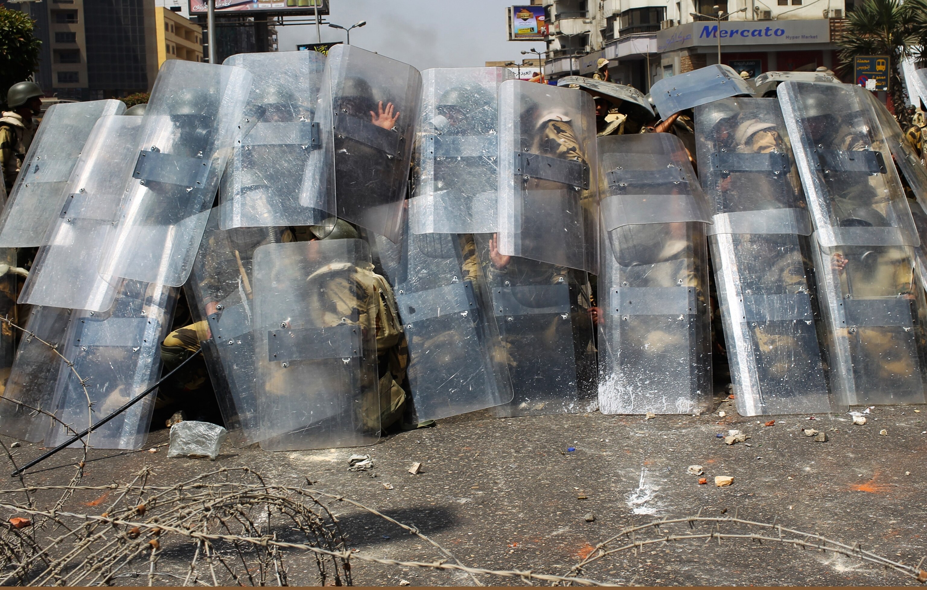 Riot police protect themselves with shields.