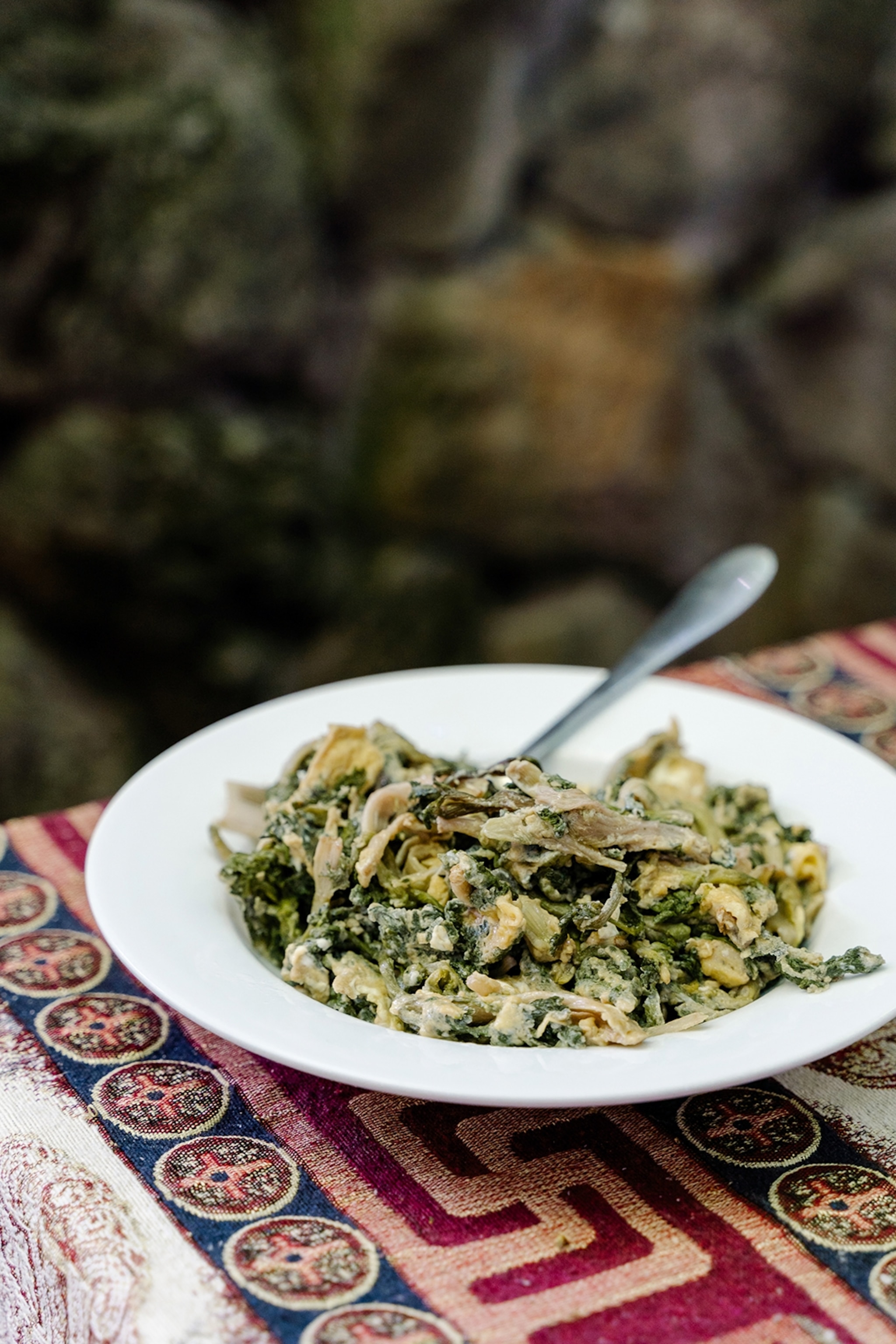 A plate of shredded pasta with an herby tarragon sauce on a traditional table clothed table outside.