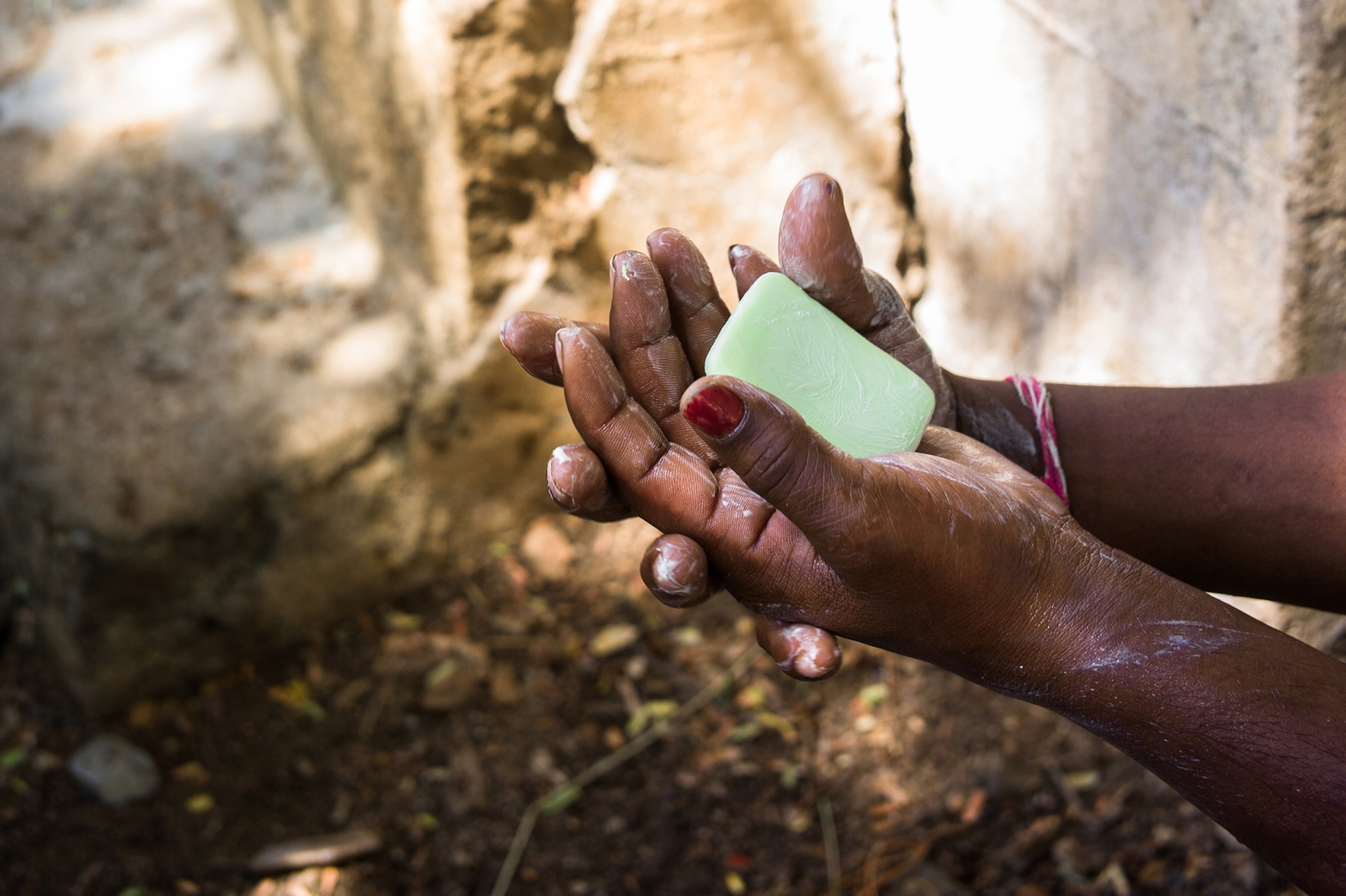 a person washing their hands with a green bar of soap