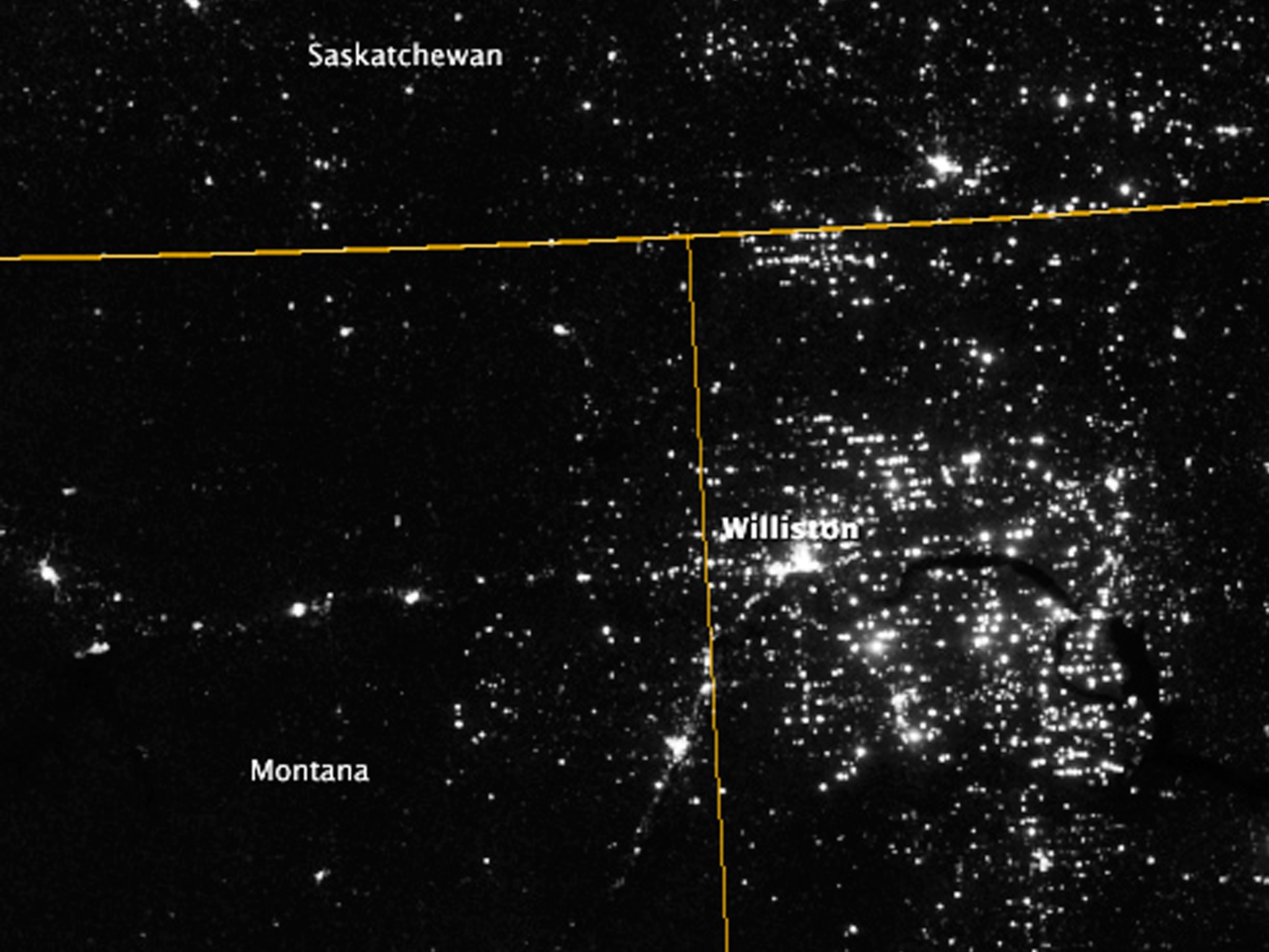 A natural gas flare illuminates discarded vehicles and farm tools.