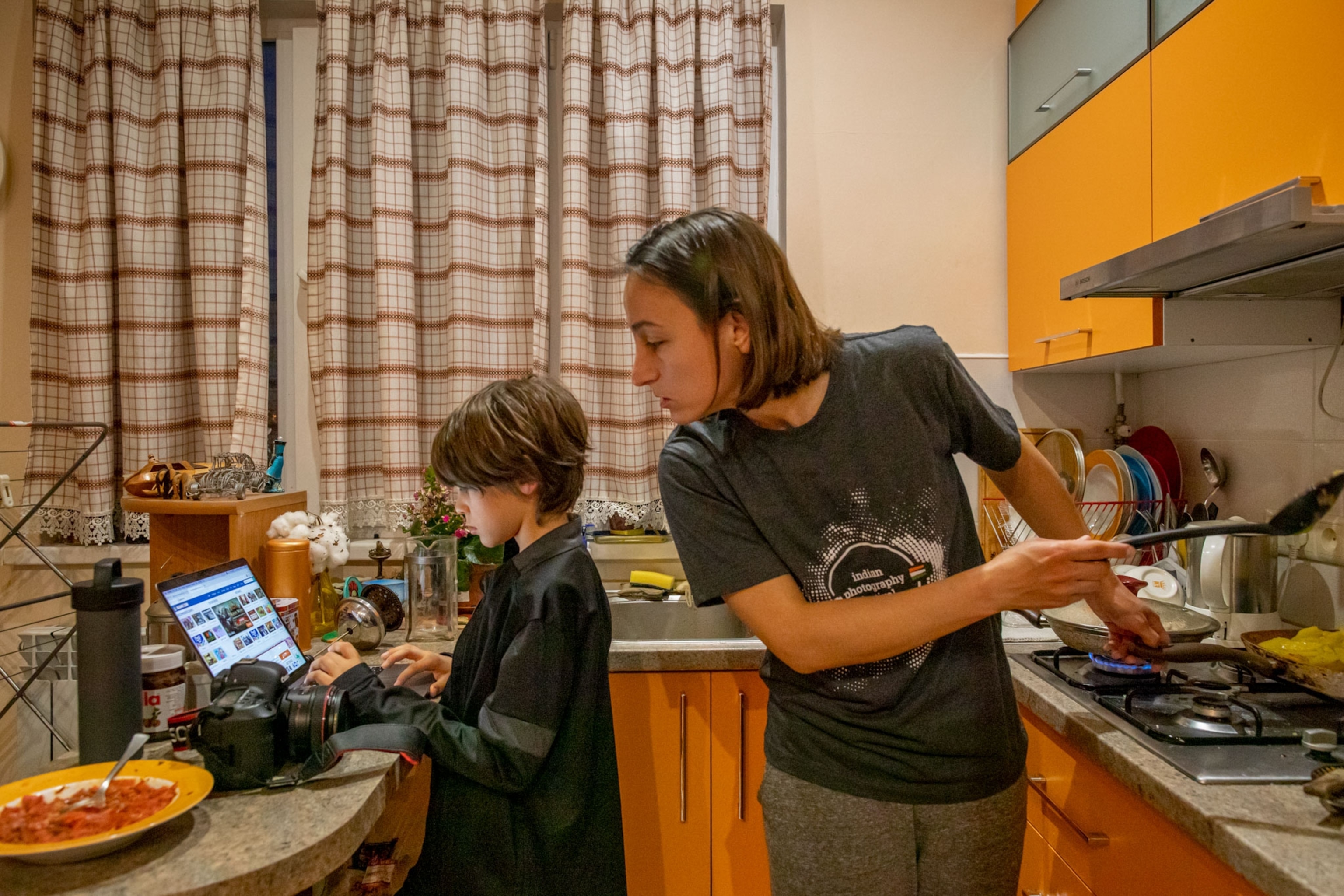 a mother watching over her son who is on the computer in Armenia