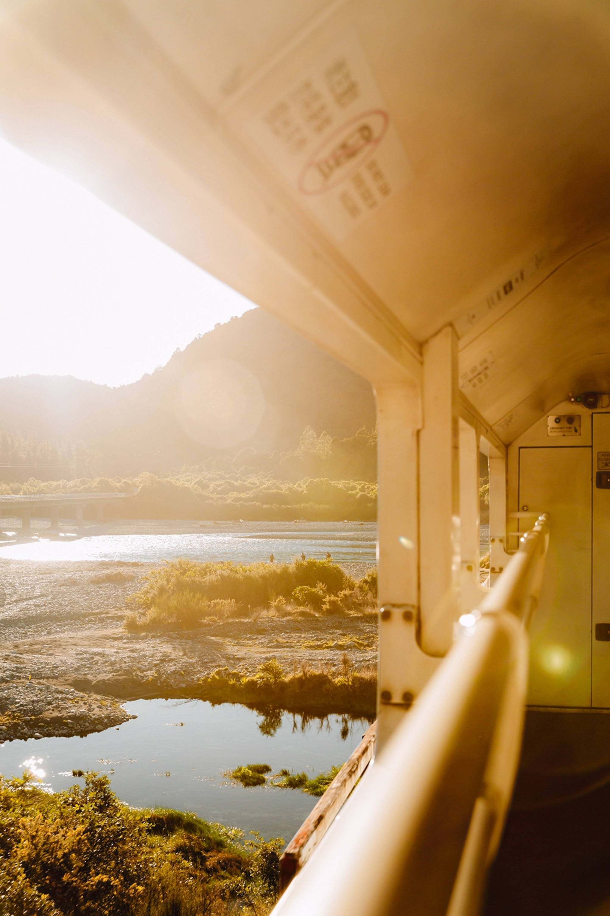 A romantic sunset shot of a lake-dotted landscape from the open-carriage views of a train.
