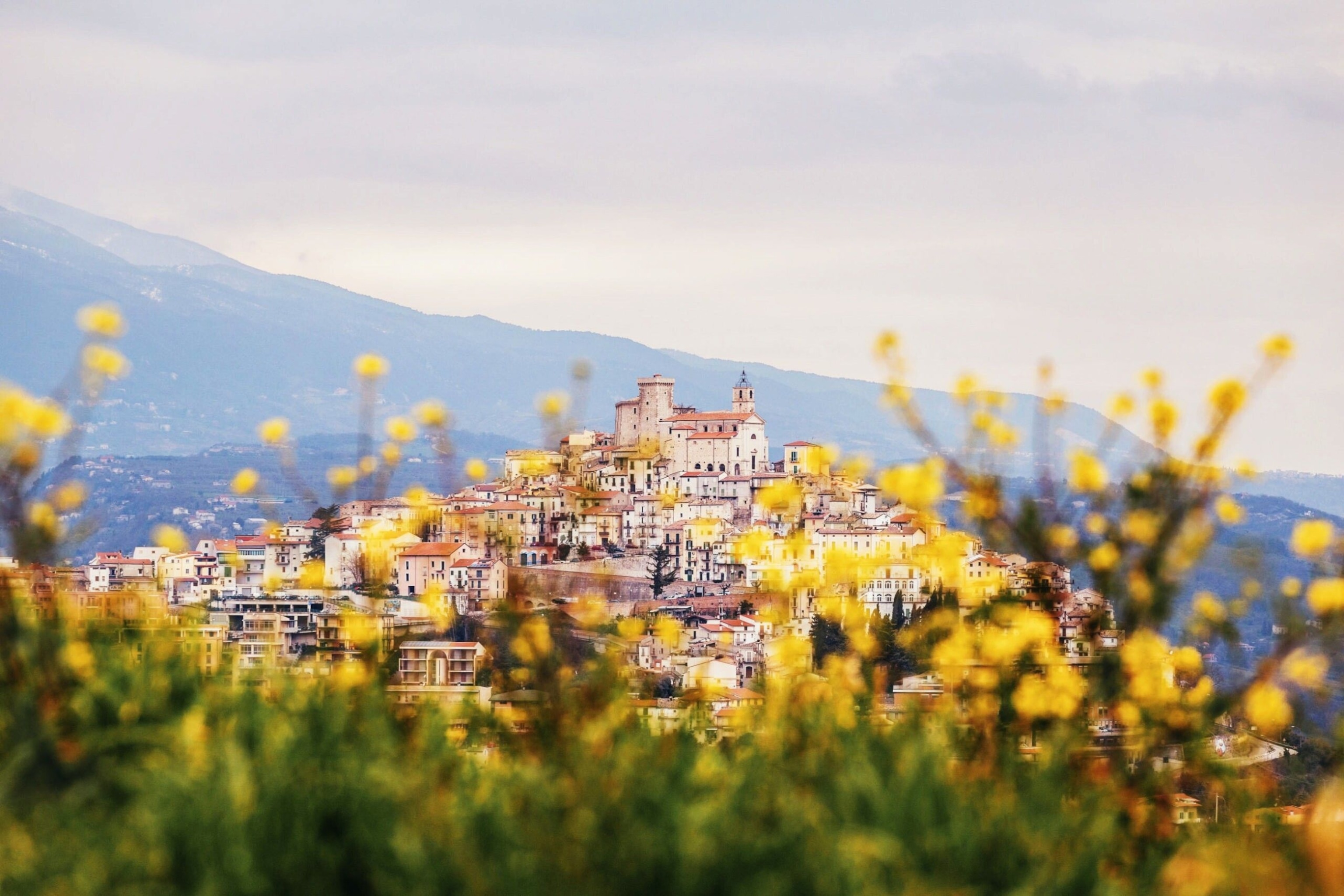 Abruzzo is on a hill. It rises to the church, which looks out over the white and brown buildings below.