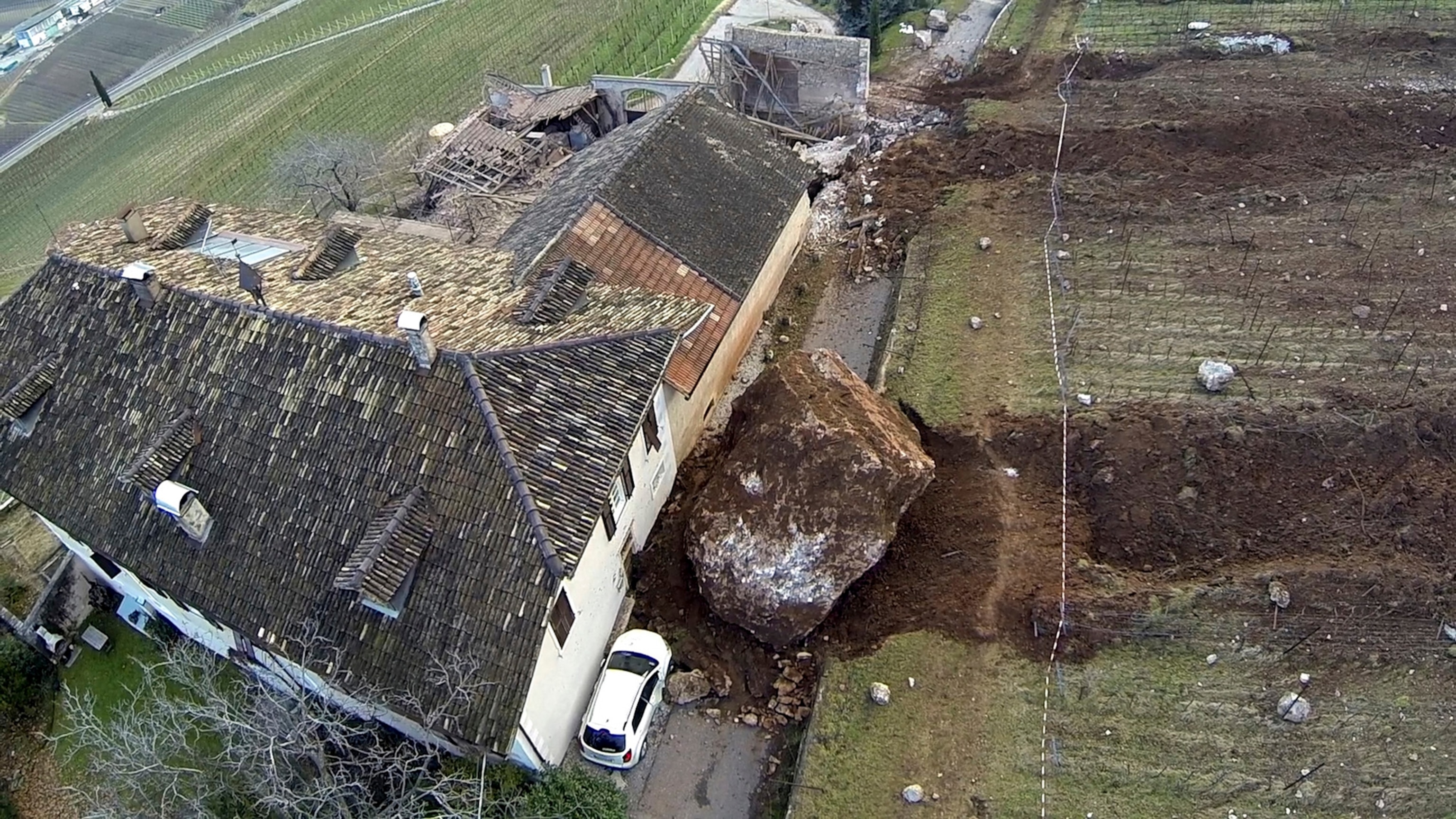 In this photo provided by Tareom.com Thursday, Jan. 30, 2014, and taken on Jan. 23, 2014, a huge boulder is seen after it missed a farm house by less than a meter, destroying the barn, and stopped in the vineyard, while a second giant boulder, which detached during the same landslide on Jan. 21, 2014, stopped next to the house, in Ronchi di Termeno, in Northern Italy.