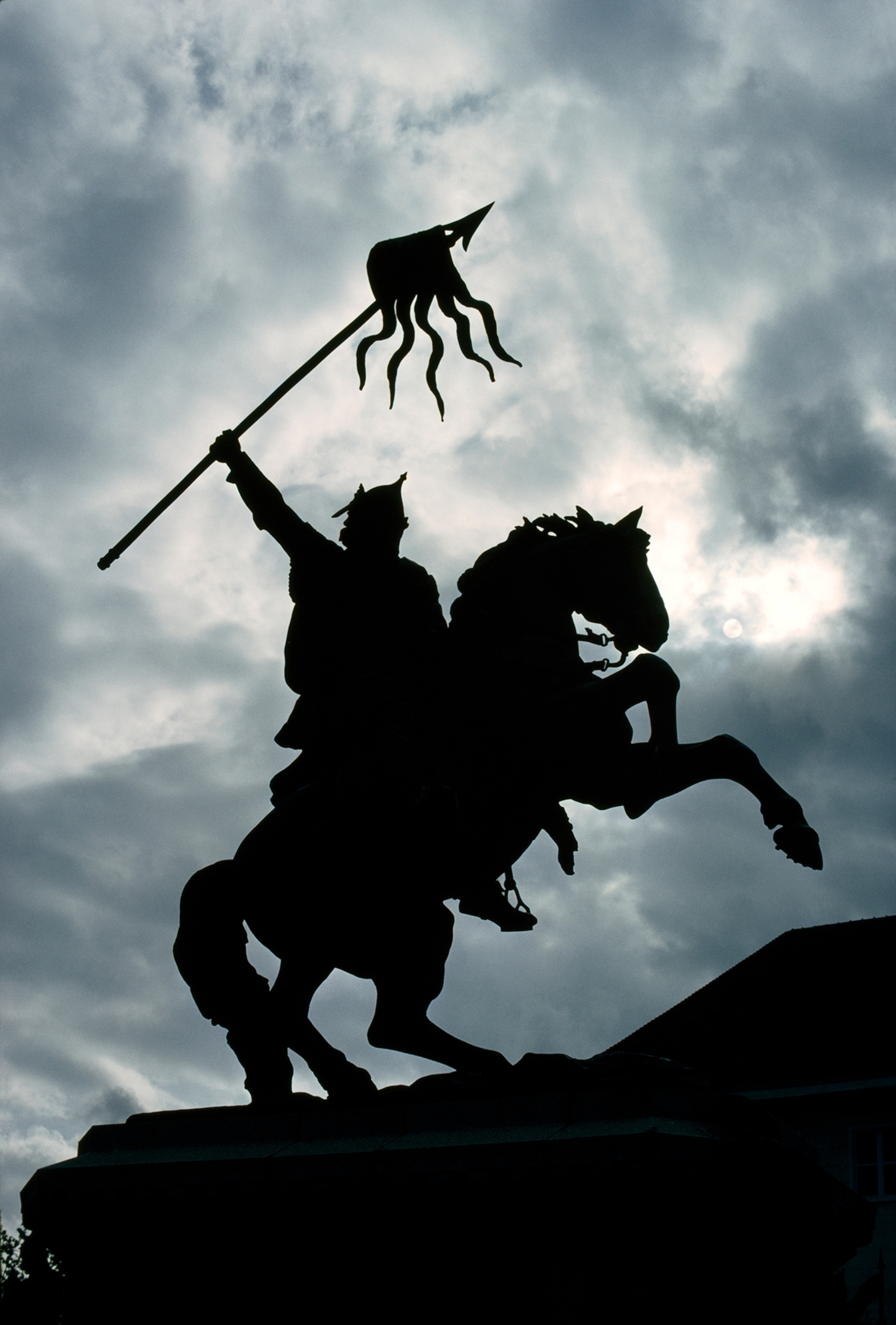 Bronze statue of William I on a horse with banner waving.