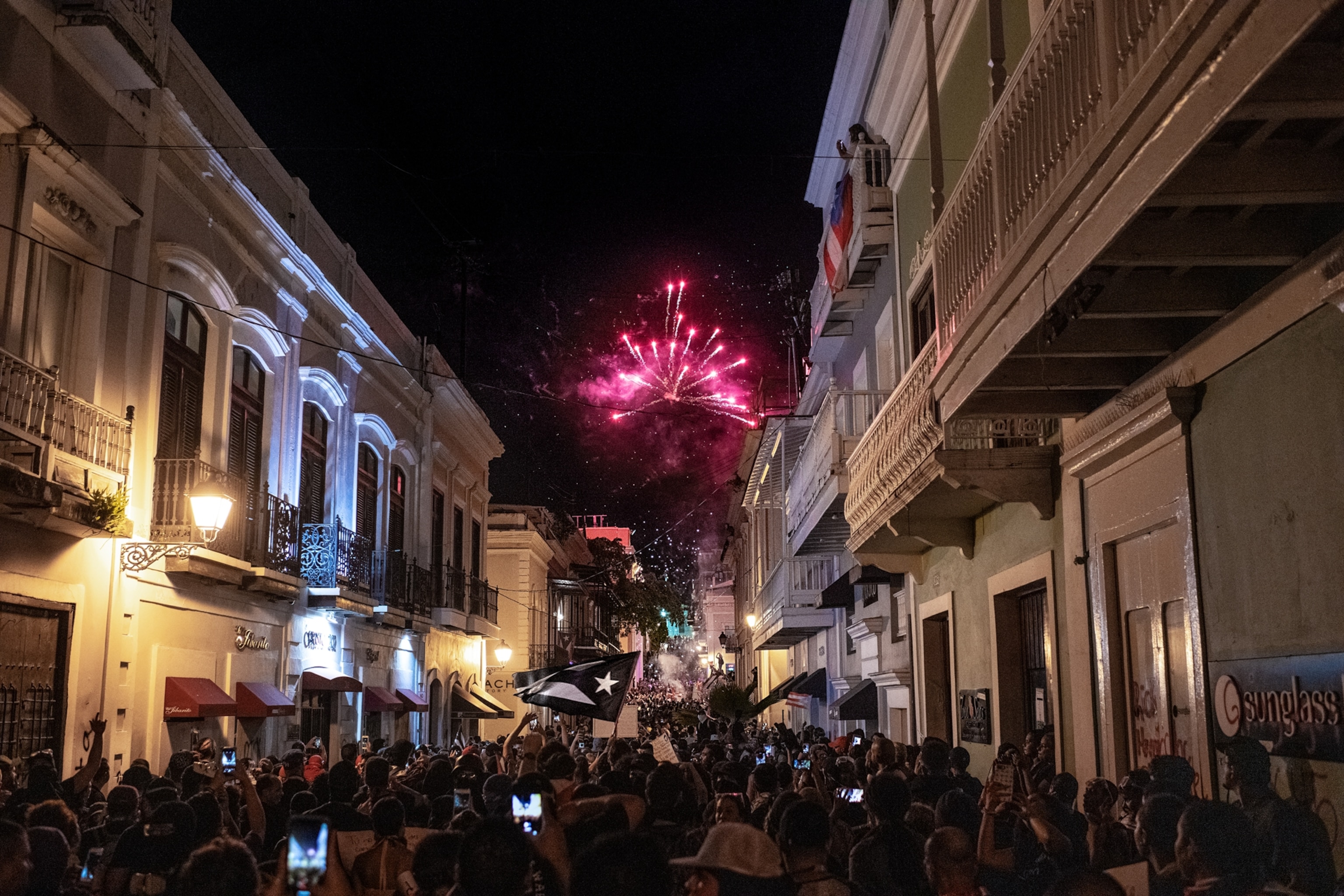 Fireworks over crowded town street.