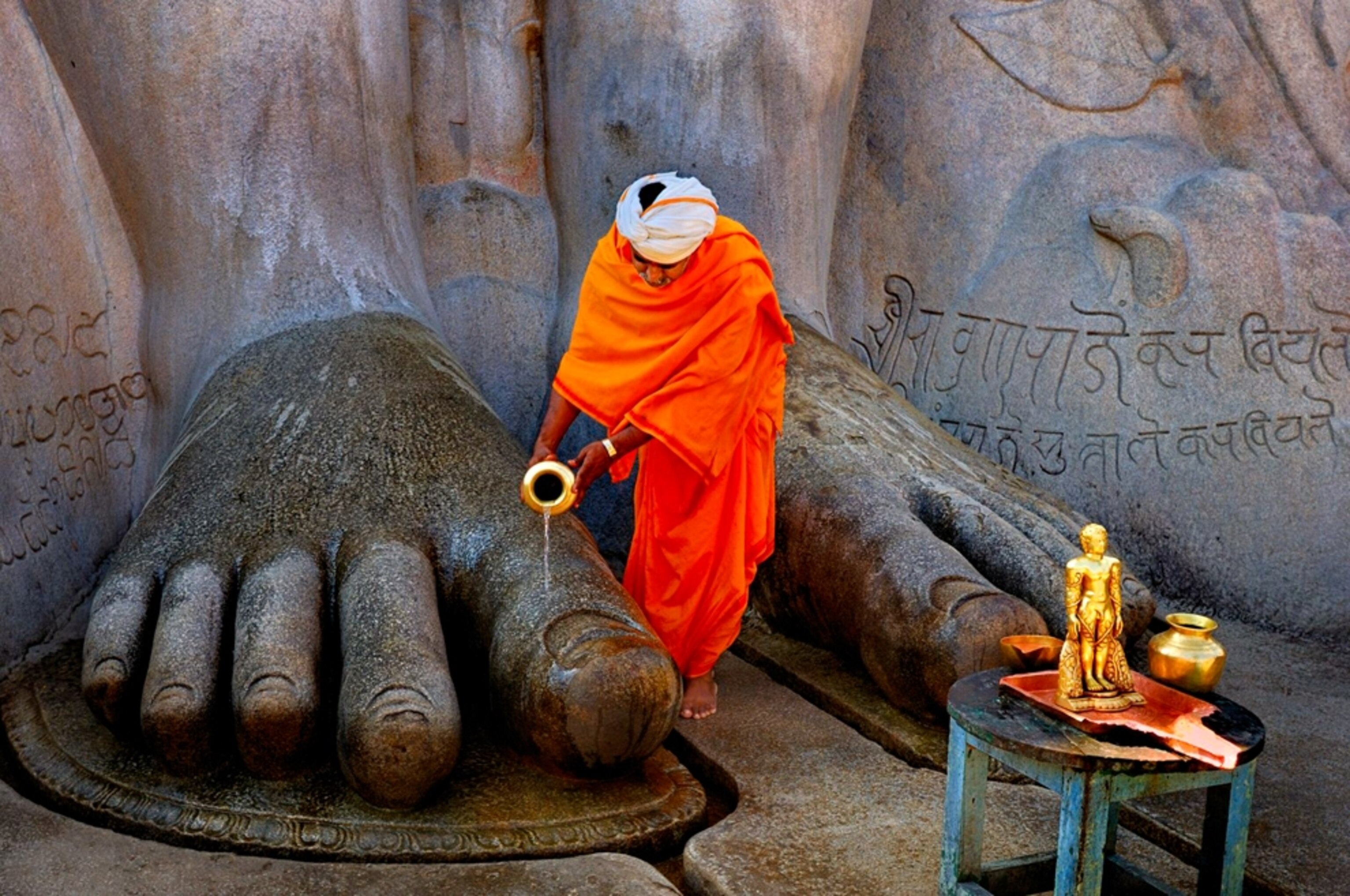 A man pours water on the feet of a large statue