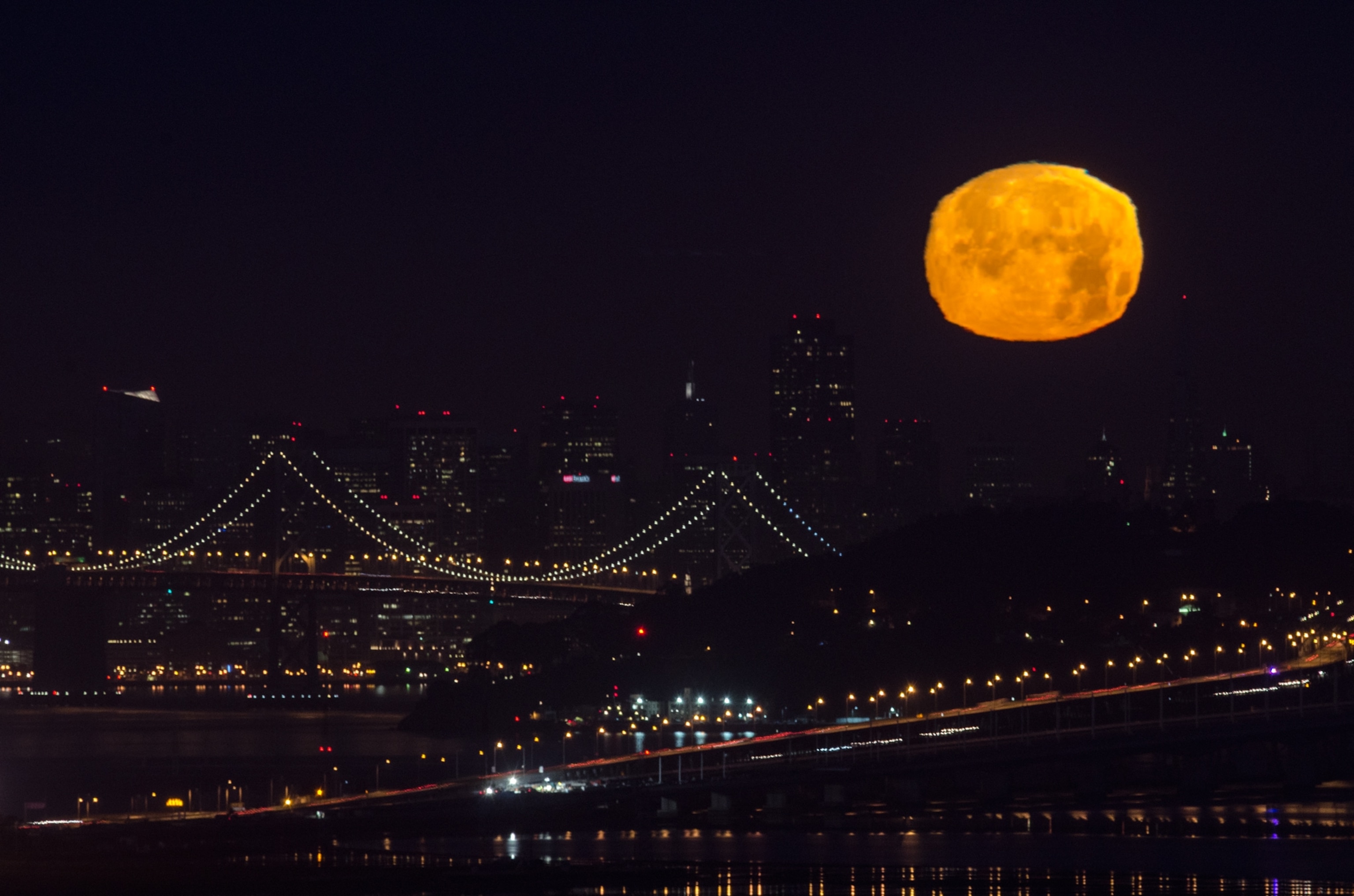 the full moon over the Bay Bridge in San Francisco, California