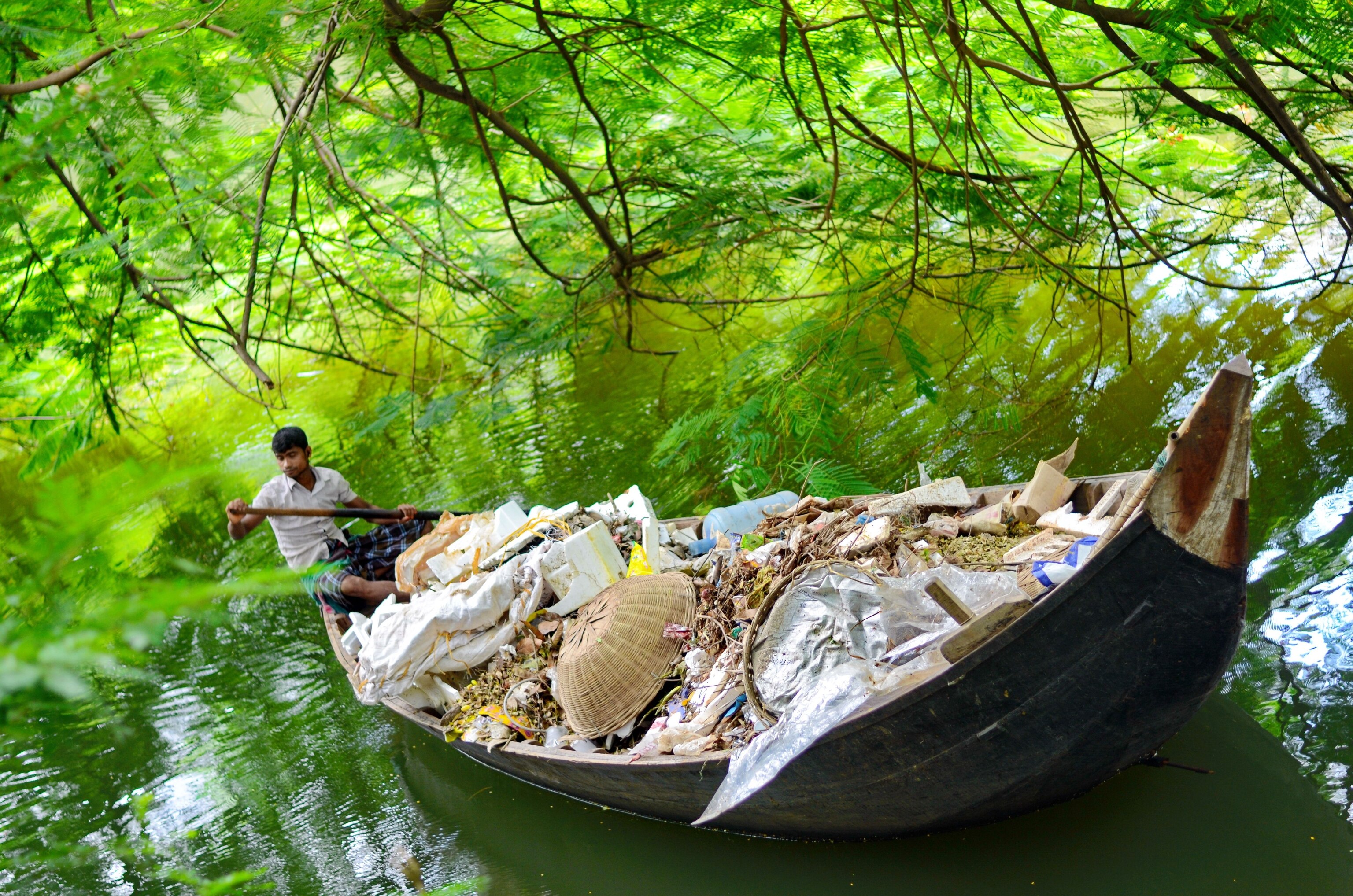 a man steering a boat full of trash