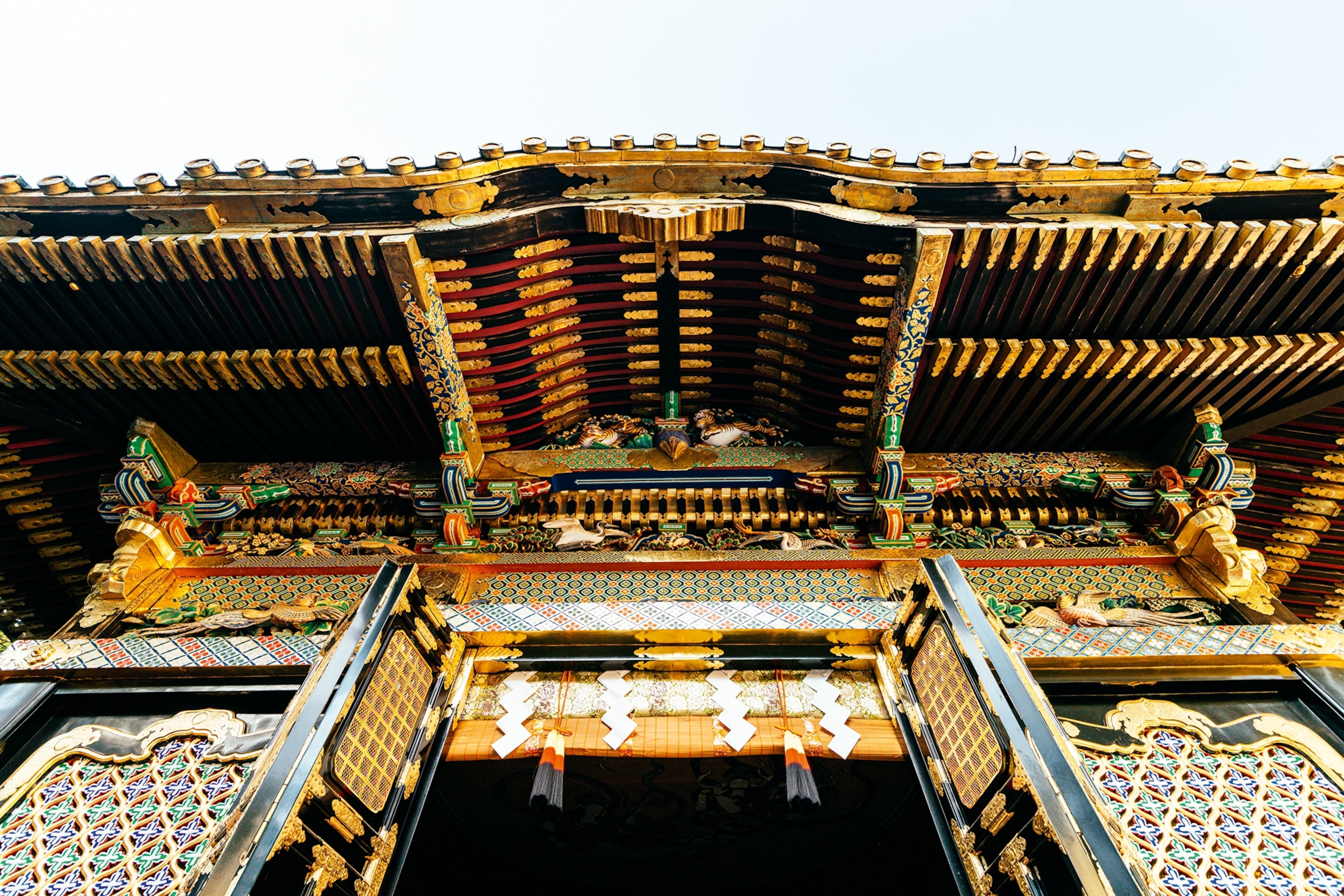 The golden and embellished facade of a Japanese temple shot from below the roof.