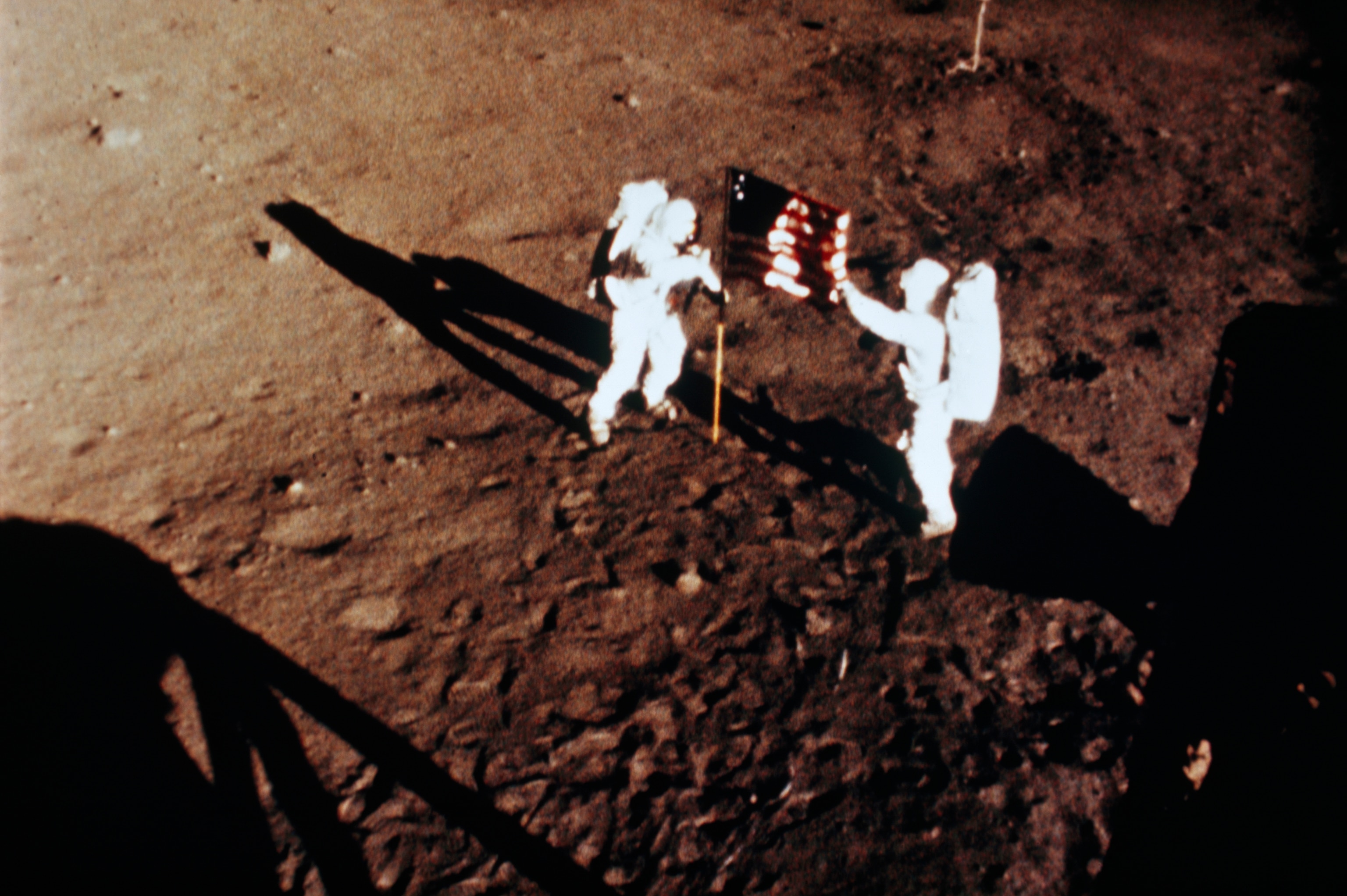 Neil A. Armstrong (left) and Edwin E. Aldrin, Jr., raise the American flag on the Sea of Tranquillity, July 20, 1969. An automatic sequence camera made the photograph.