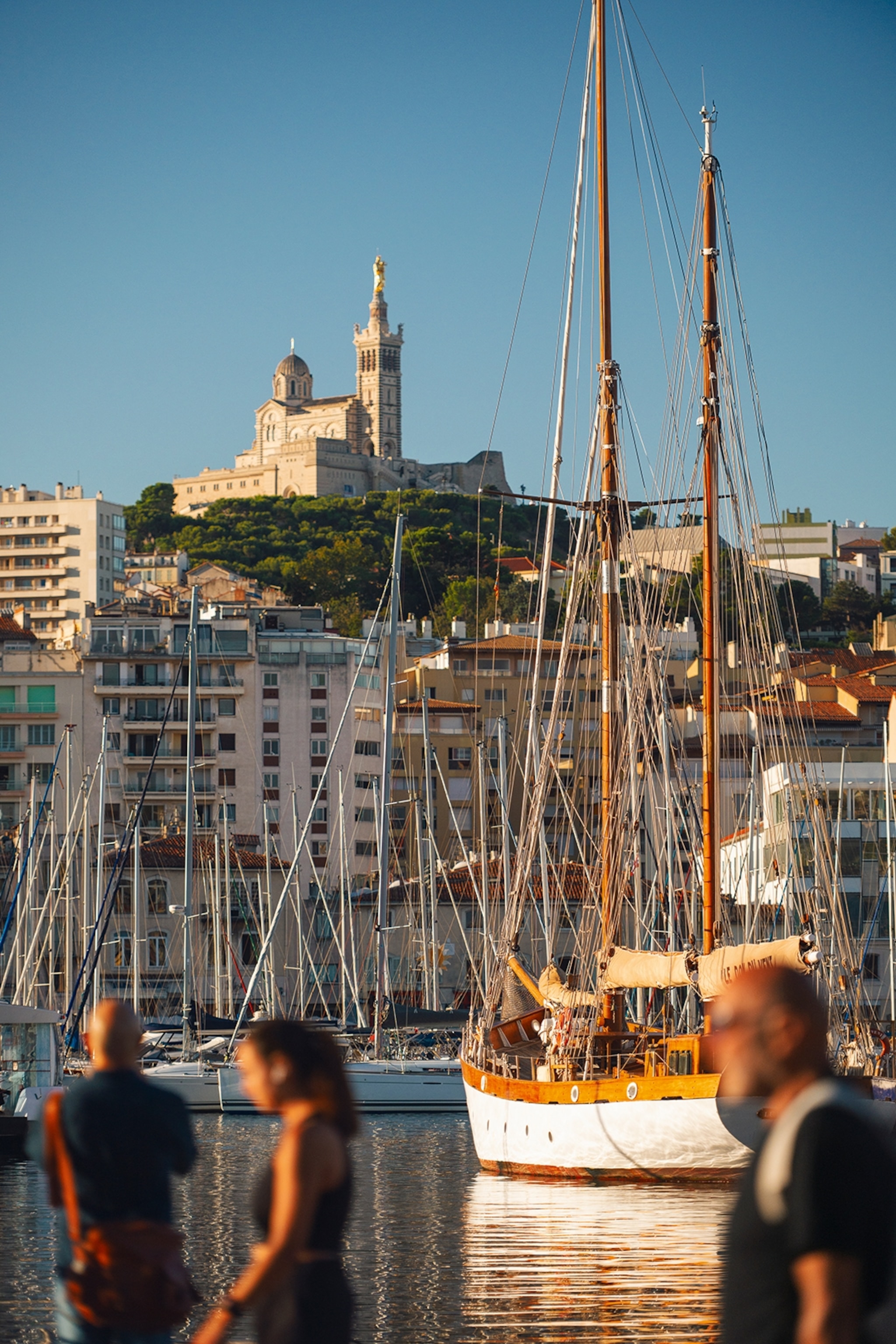 The harbour of a French city with a dome towering over it from a hill.