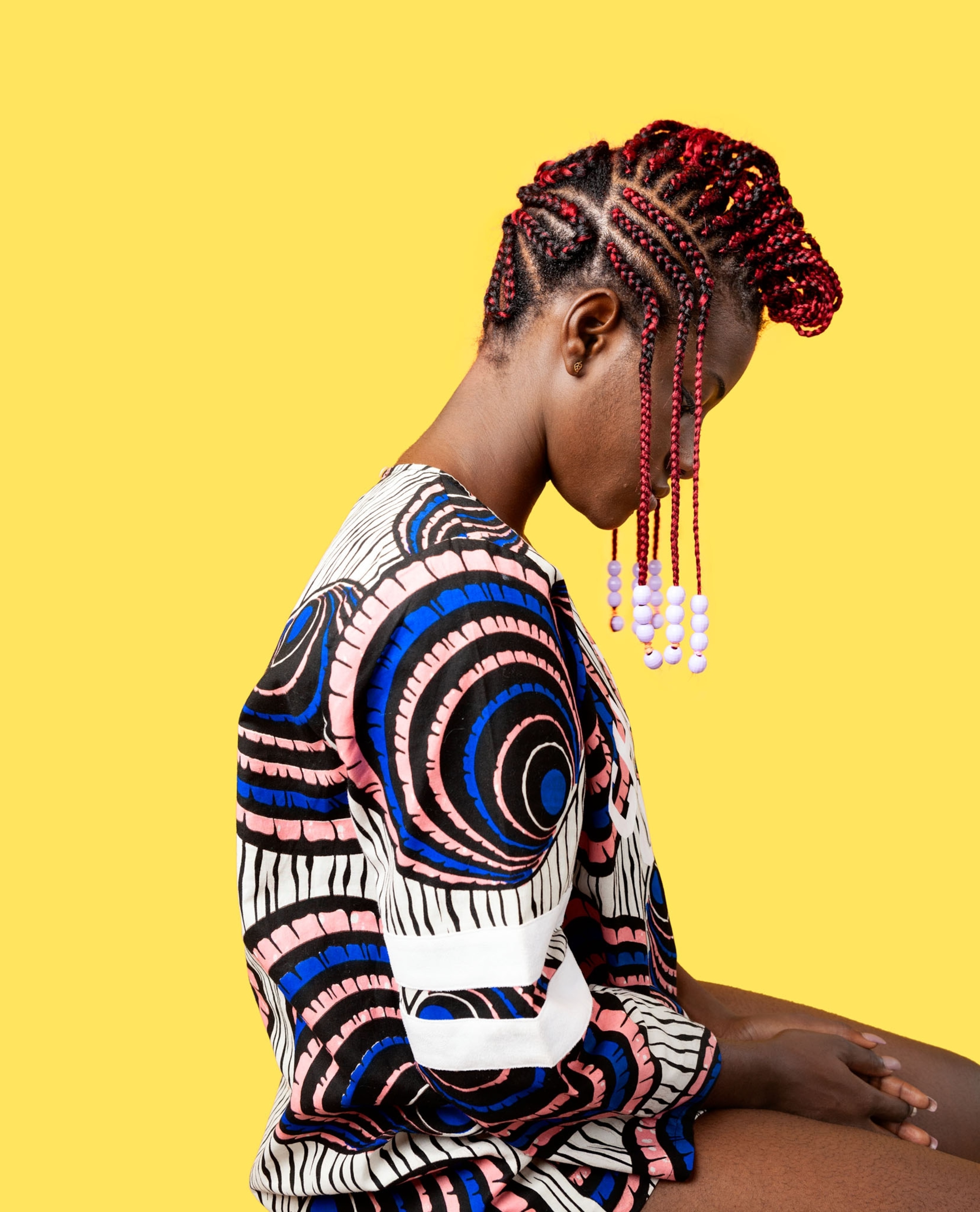 Picture of woman with hair is divided vertically down the middle and braided with magenta thread horizontally to the division. Lavender beads added to side ends.