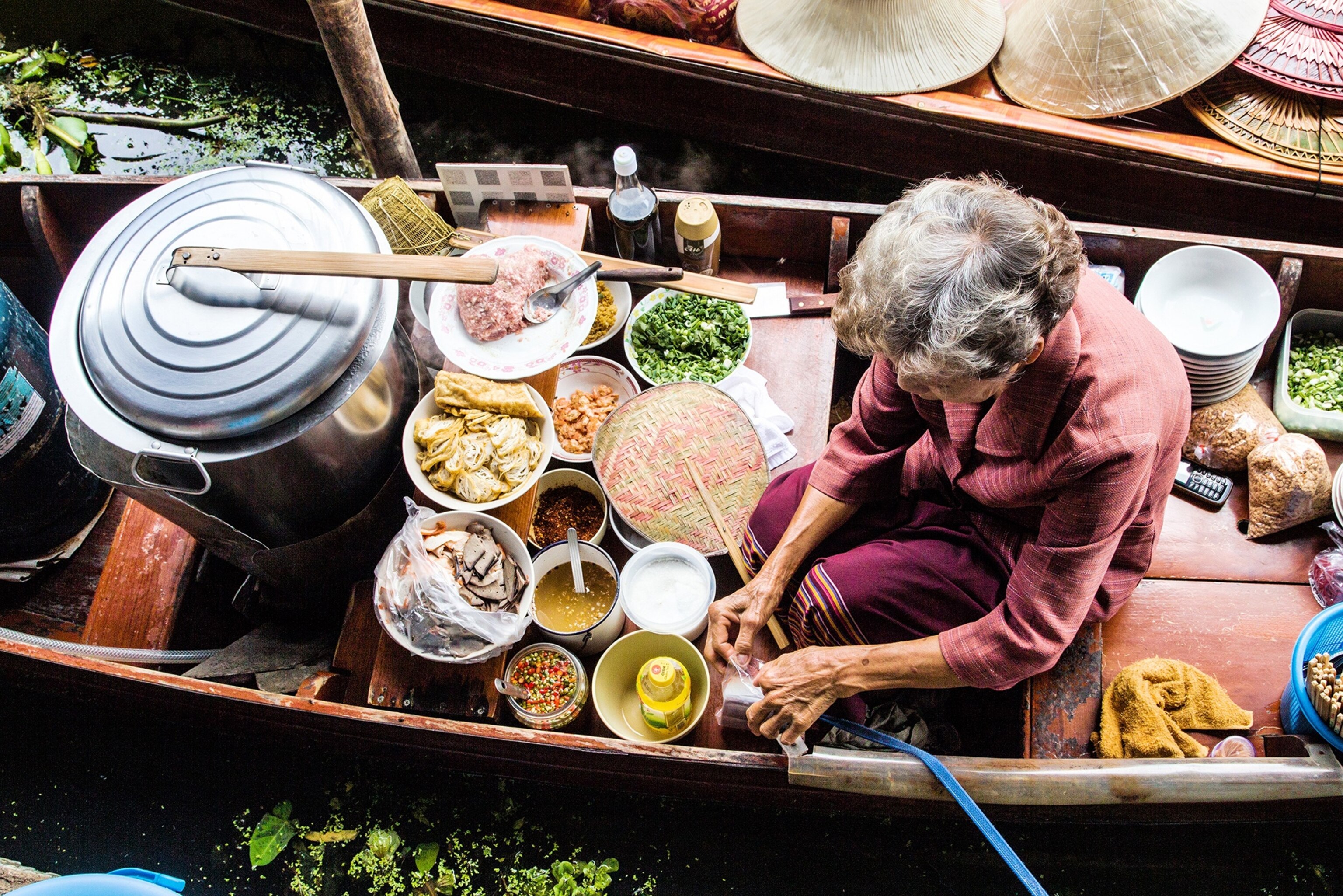 An old women preparing her cooking ingredients to sell the food on Moe Klong River floating market, damnoen saduak, Thailand.