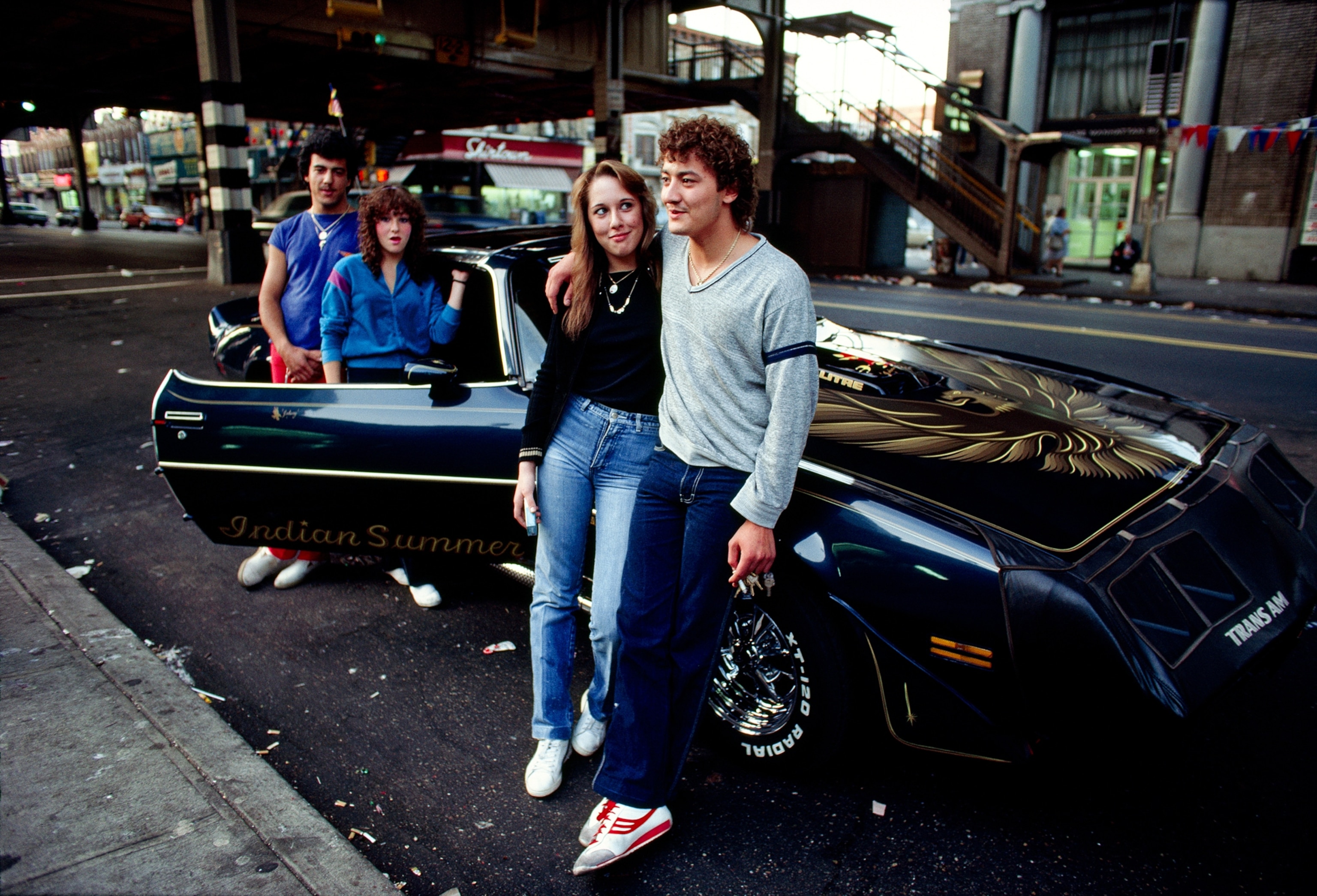 Eighties Photos - Two teenage couples from 1983 standing in front of their trans-am sports car.