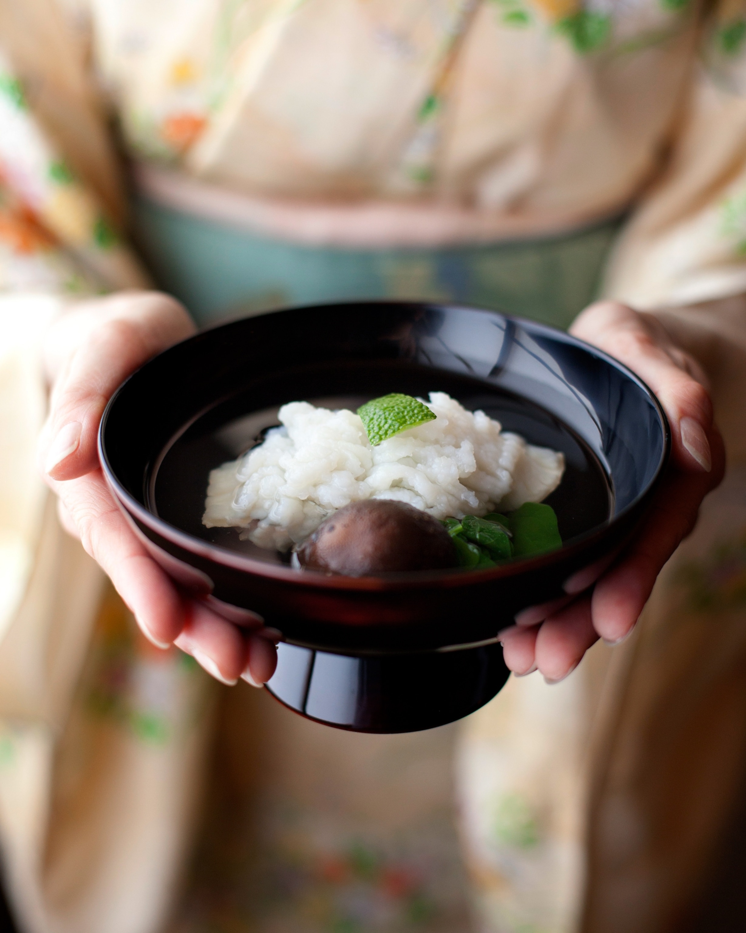 A woman holding up a bowl of soup