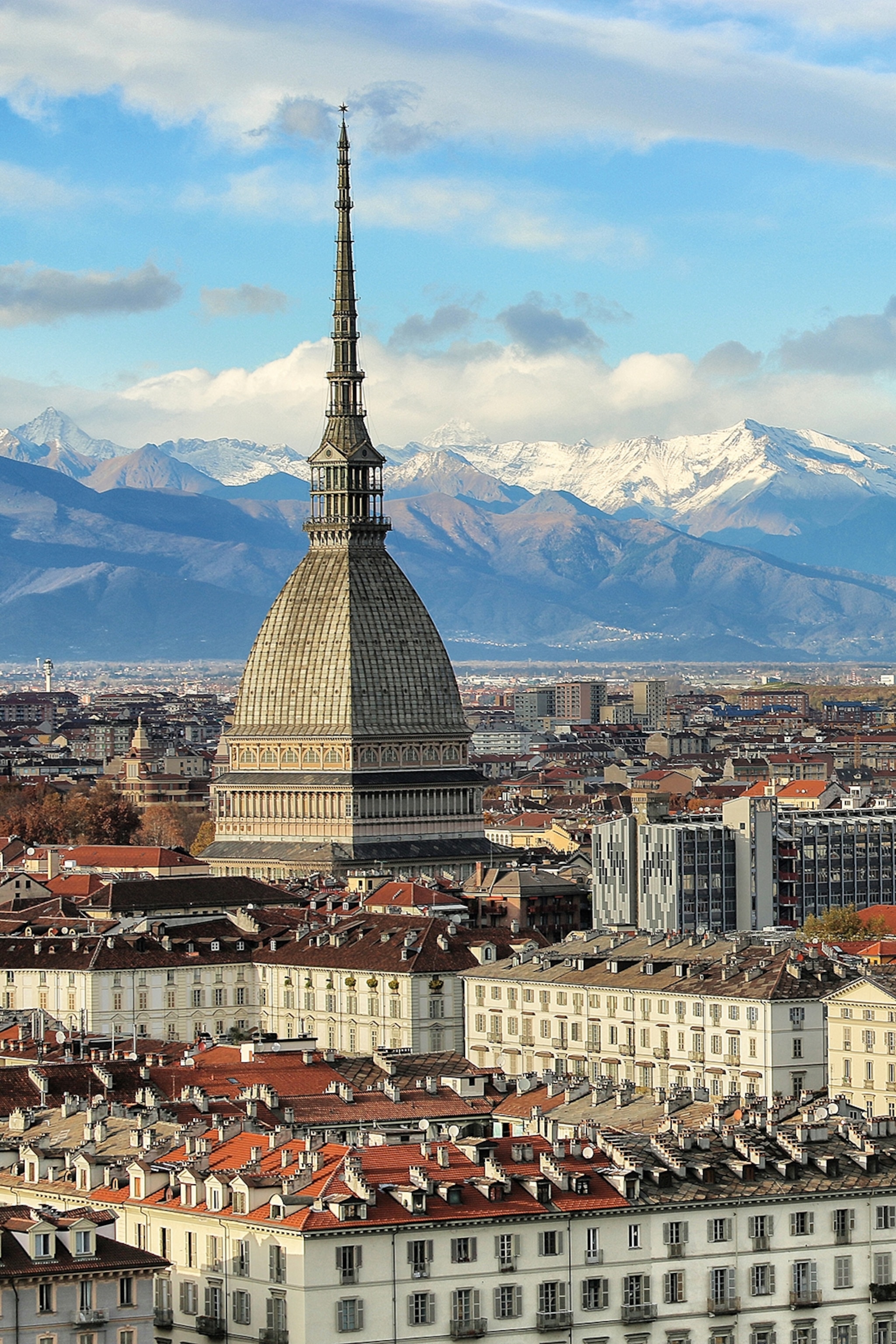A city shot from above with a chapel dome peaking out as mountain peaks fill the background.