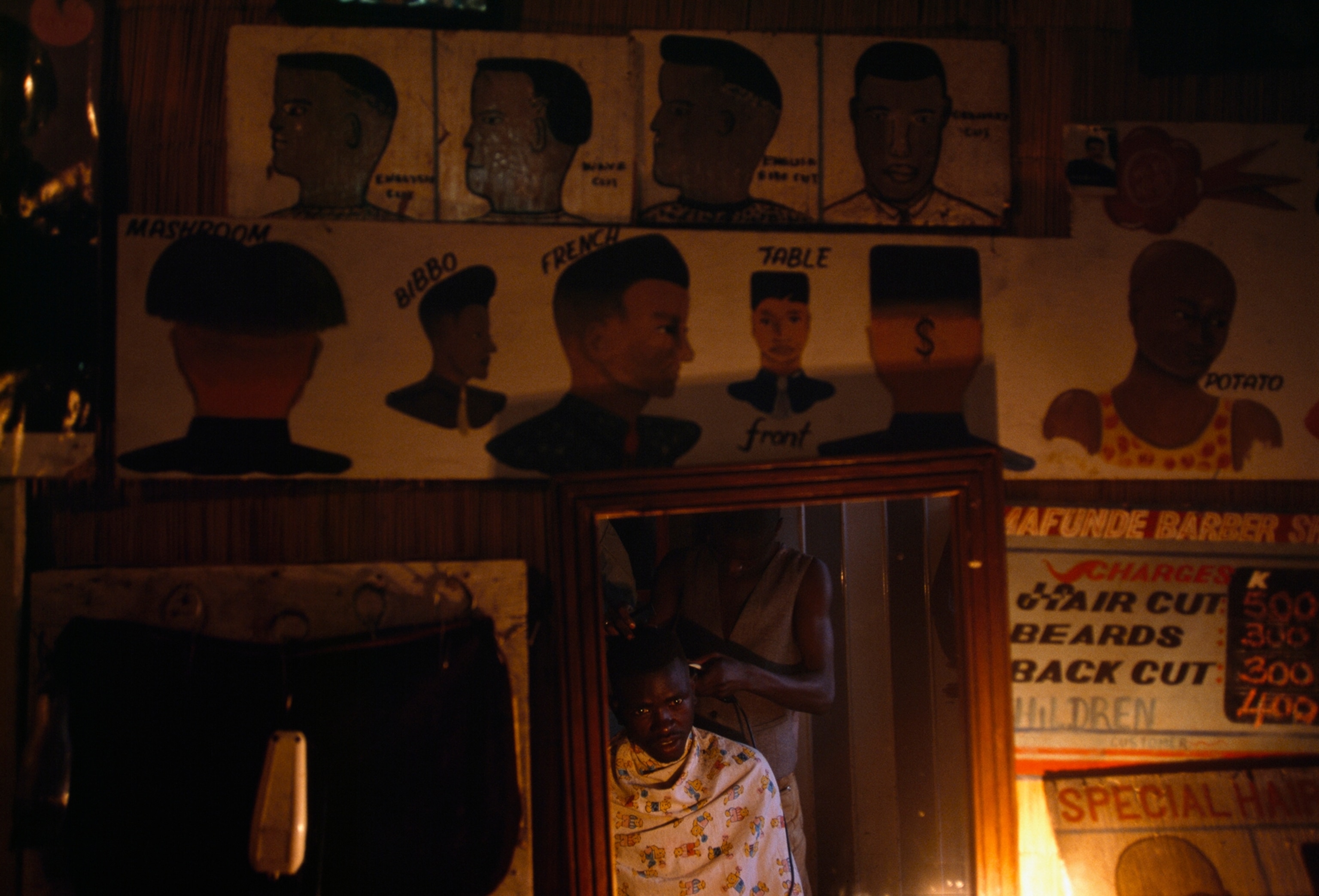 Drawings of various hairstyles decorate the interior of a barber shop in the Maramba market.