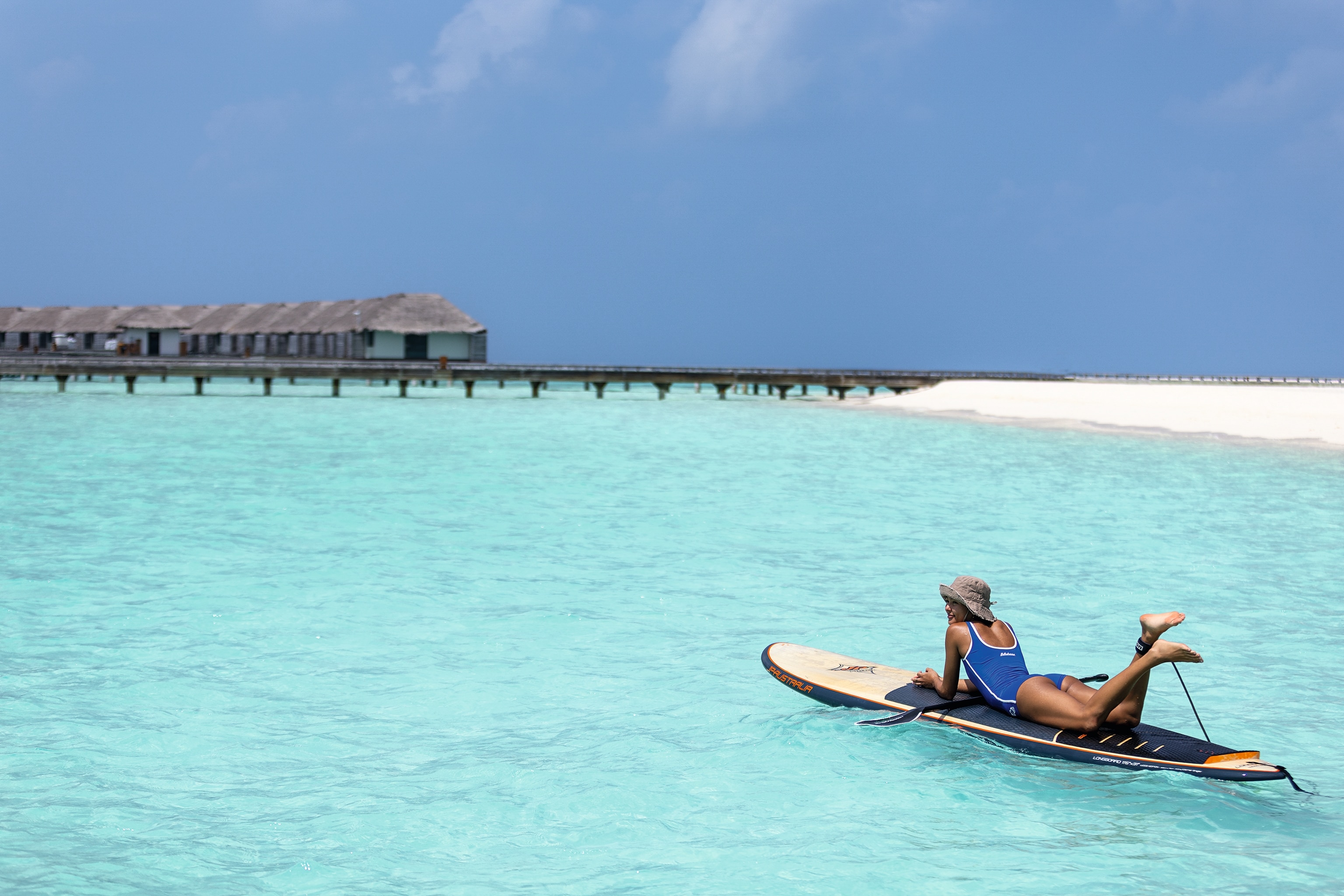 A woman relaxing on a surfboard looking out over the clear blue water