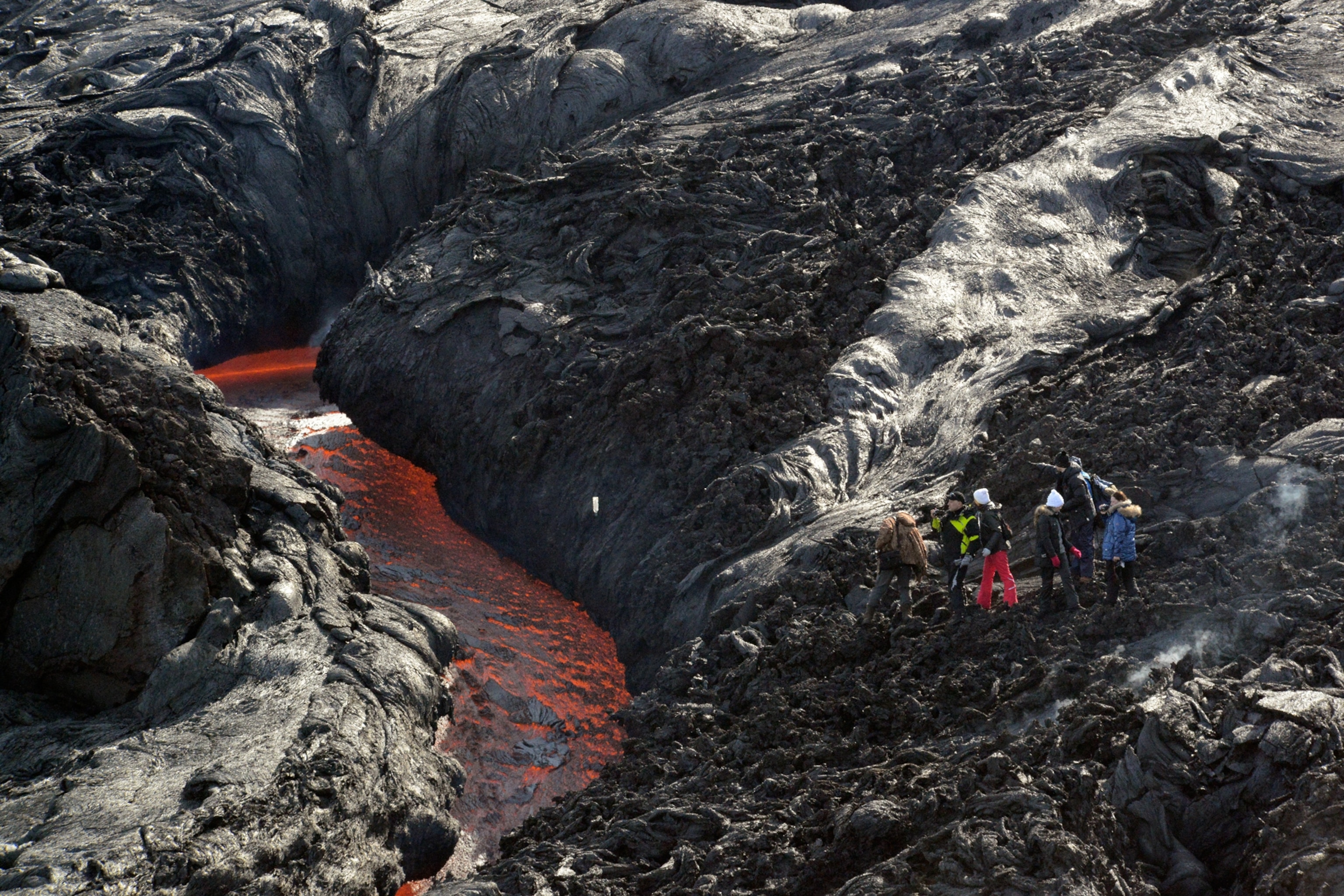 lava flowing down a canyon carved through previous lava deposits in Kamchatka