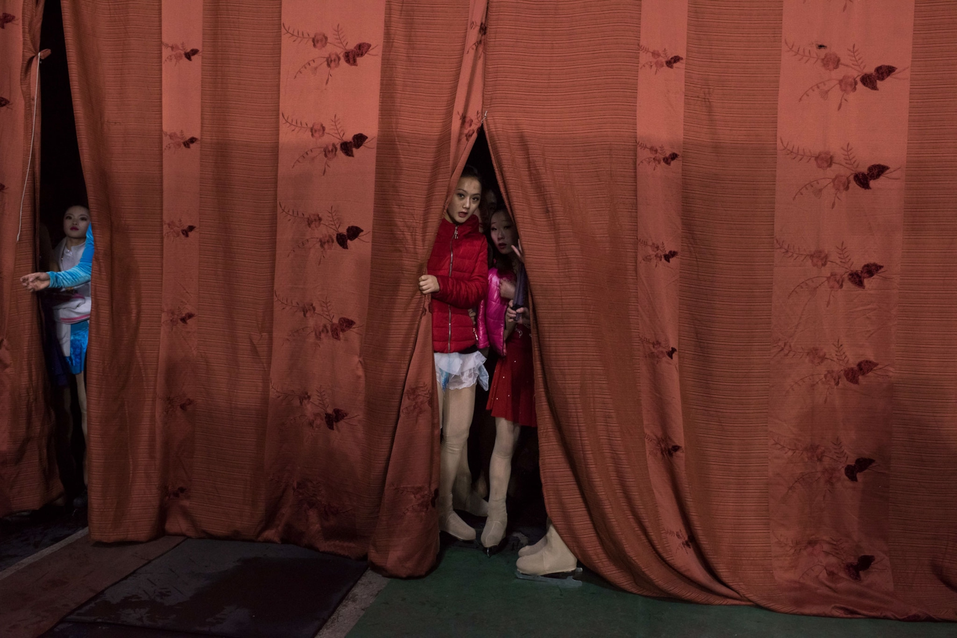 a girl peering through a curtain in North Korea