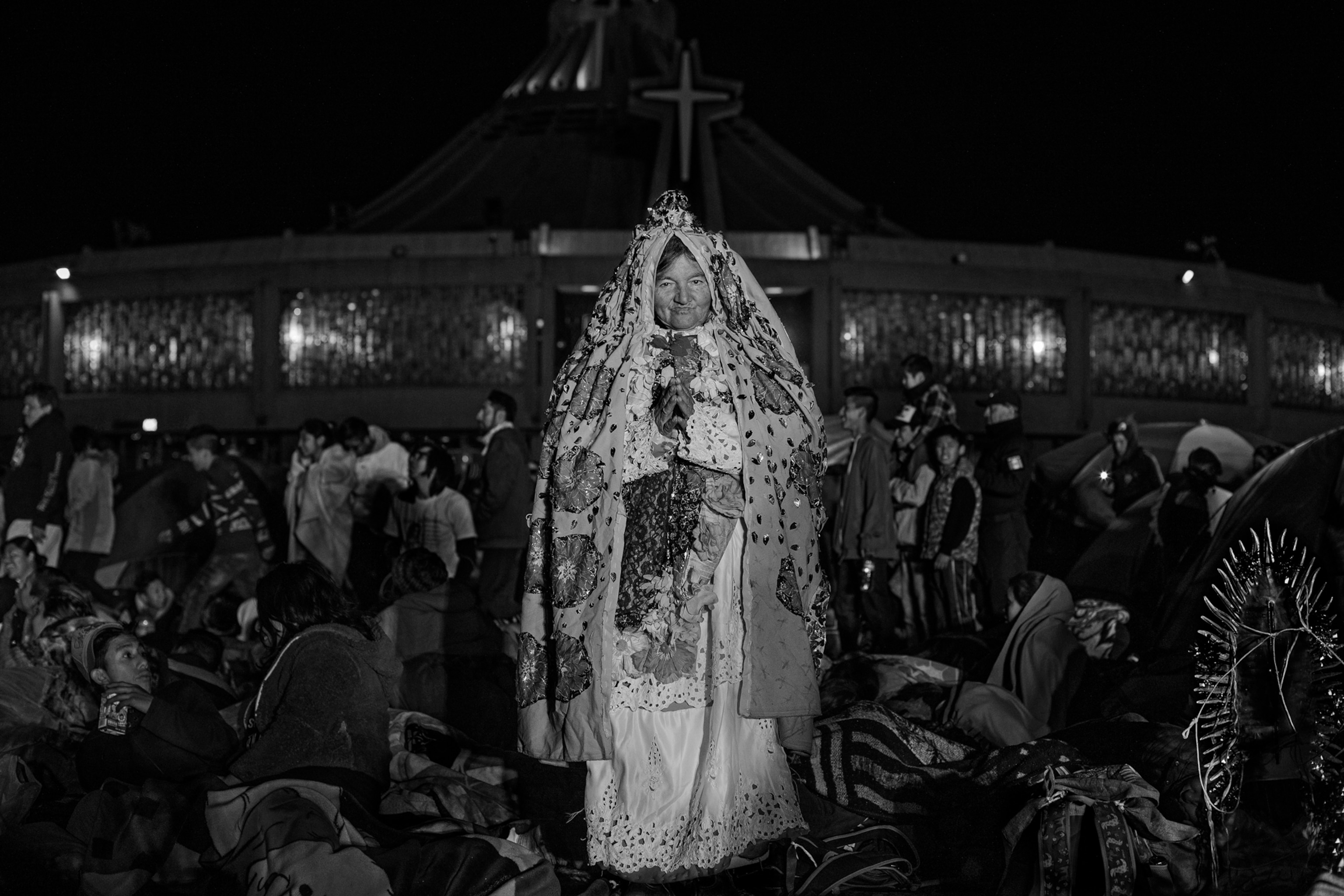 A woman in a white dress stands in front of a church
