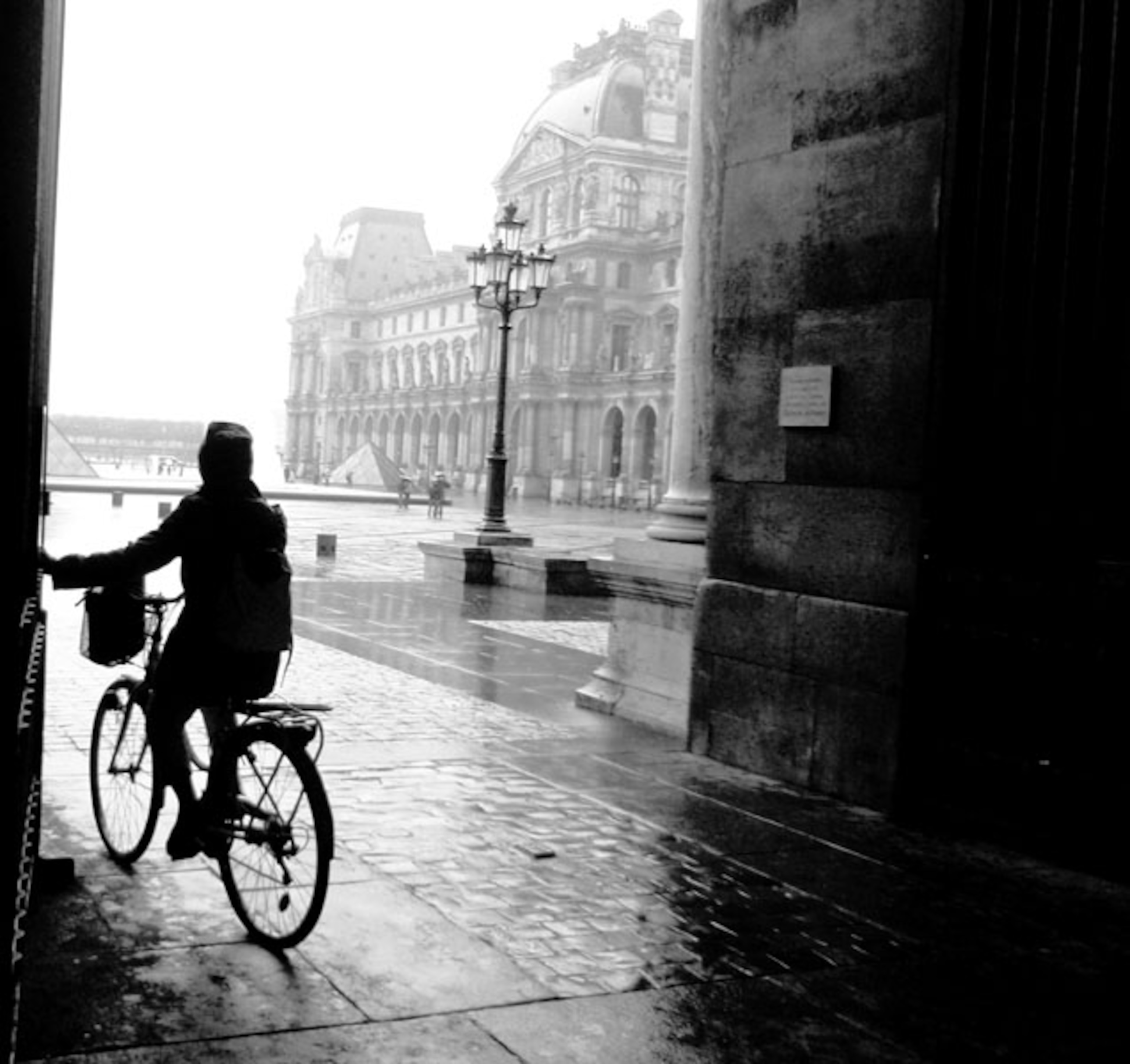 A woman bicyclist seeking shelter from rain in Paris, France