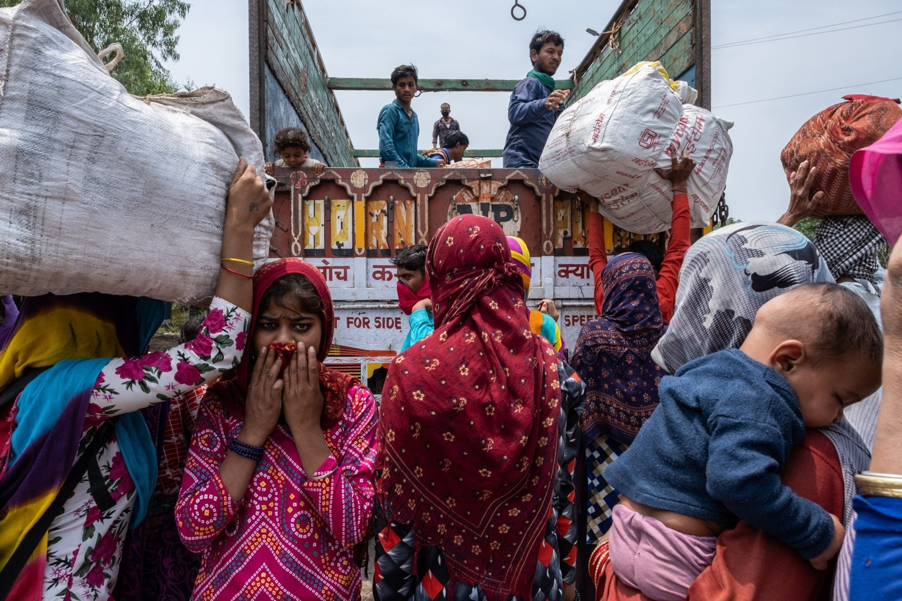 a few people in the back of a truck, while many others stand outside of it