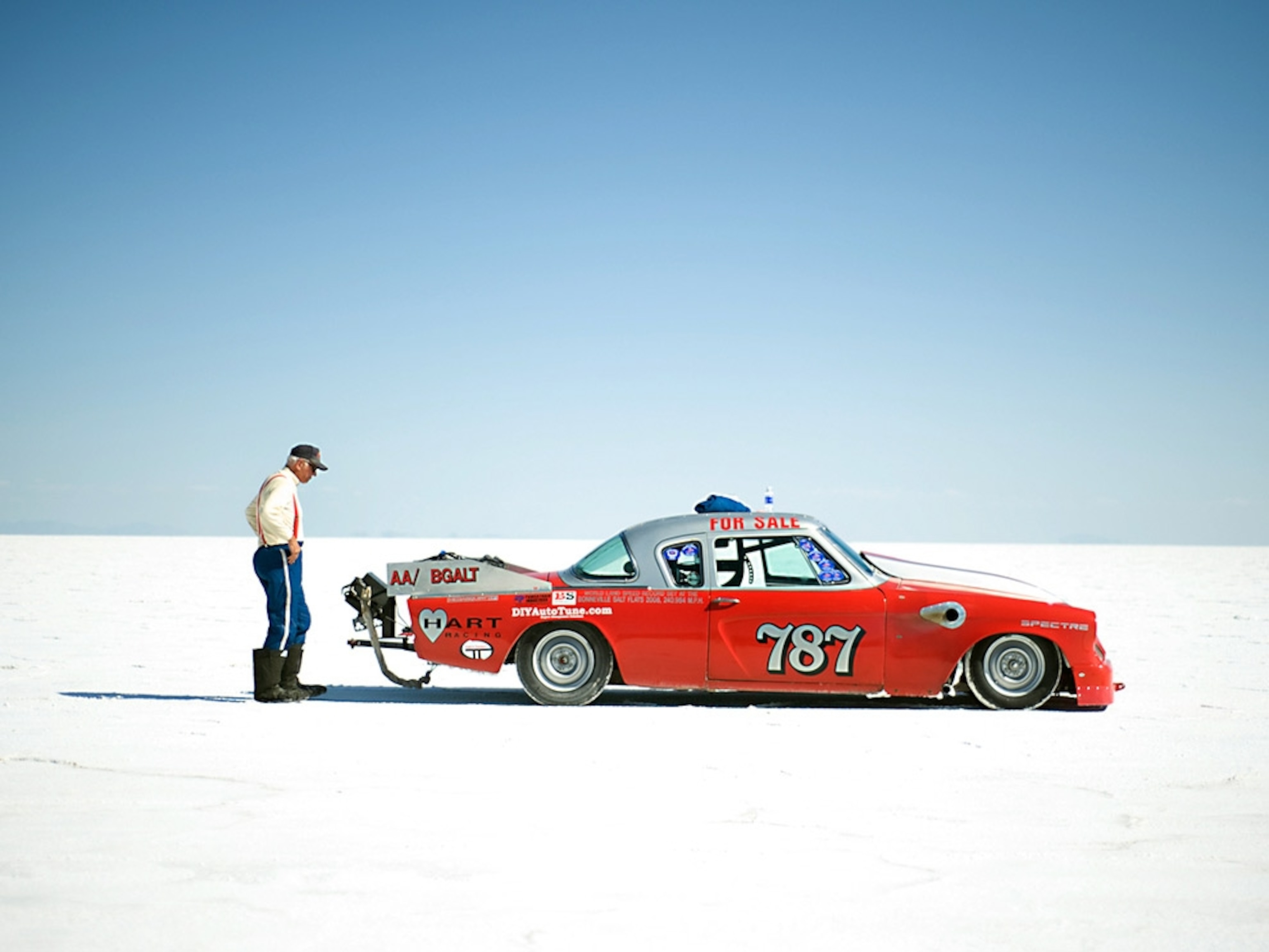 Racer standing behind his car on salt flats