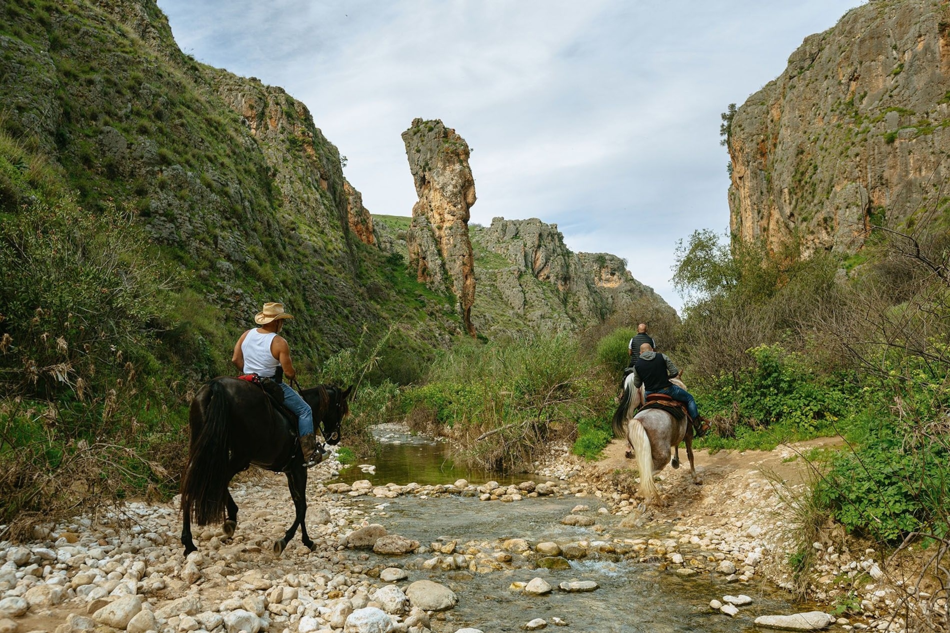 A group of horse-riders on the trail below the Amud, a striking limestone pillar rising from a stream of the same name, Upper Amud Stream Nature Reserve.
