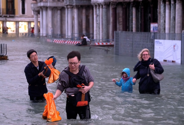 People trudge through the square, trying to keep their belongings dry.