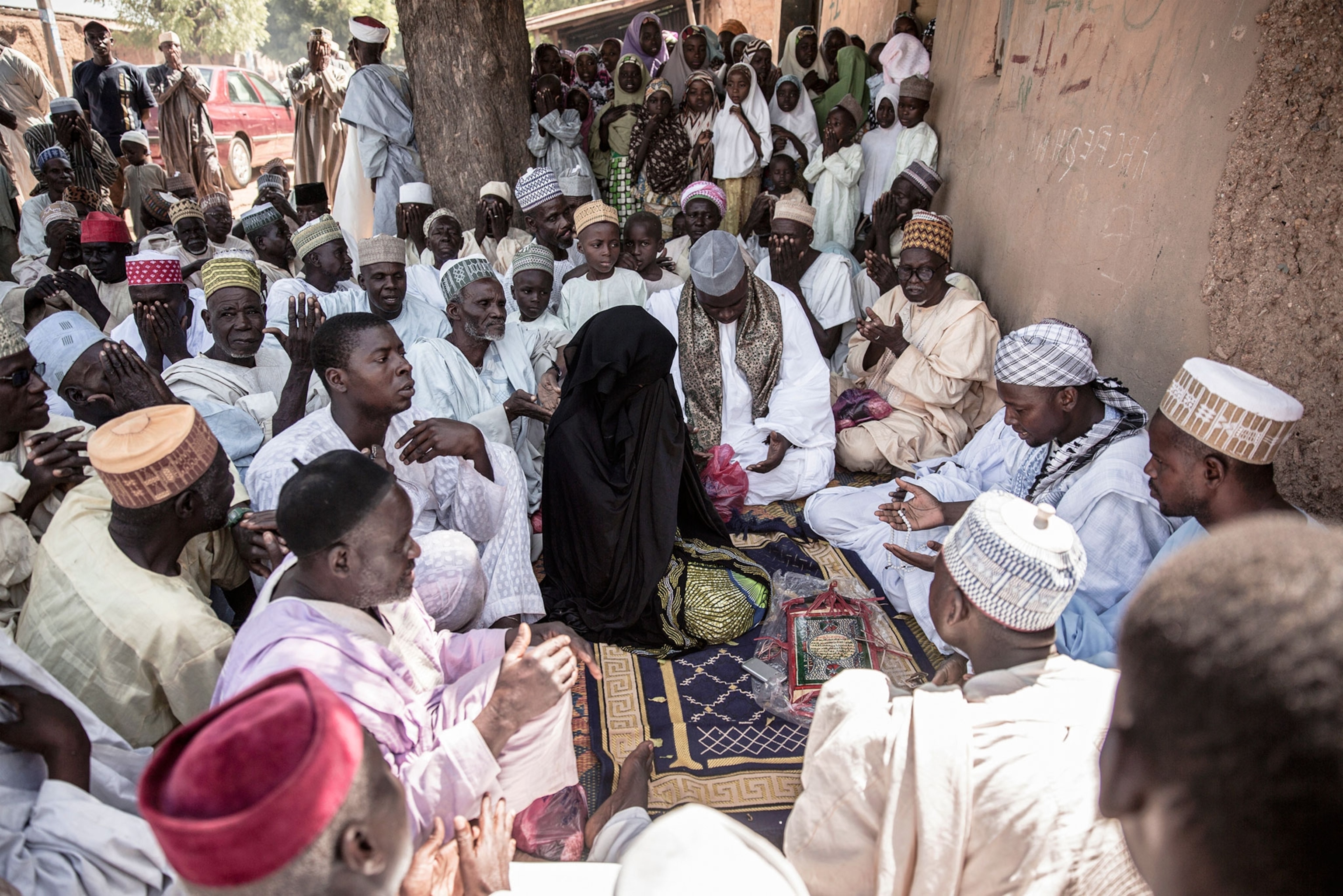 The wedding fatiah of a village girl. A contract is announced and the men of the village say prayers and recite blessings. Women rarely interact with men who are not their relatives.