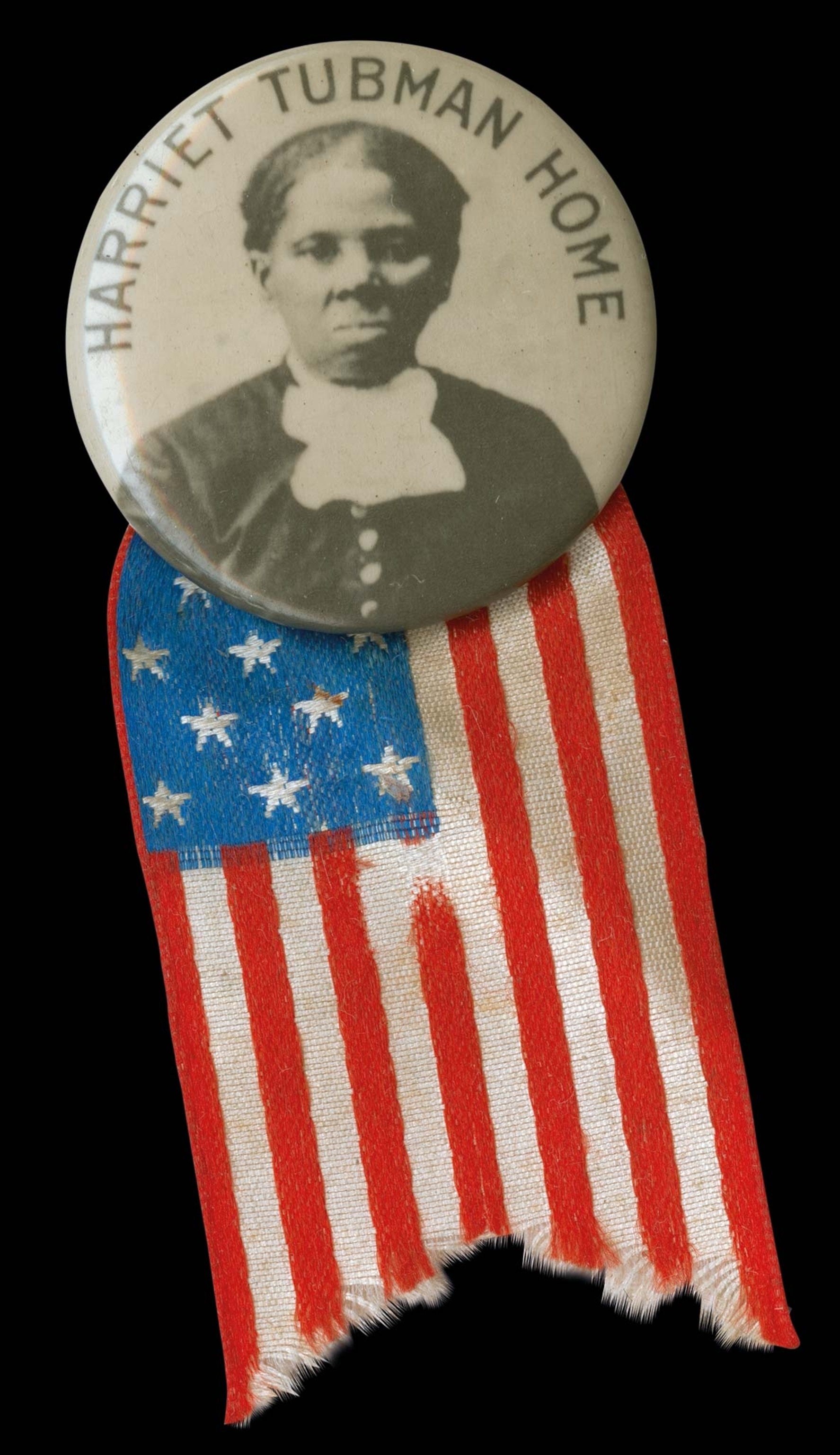 A pin with a photo of Harriet Tubman, text reading "HARRIET TUBMAN HOME," and an American flag pennant attached