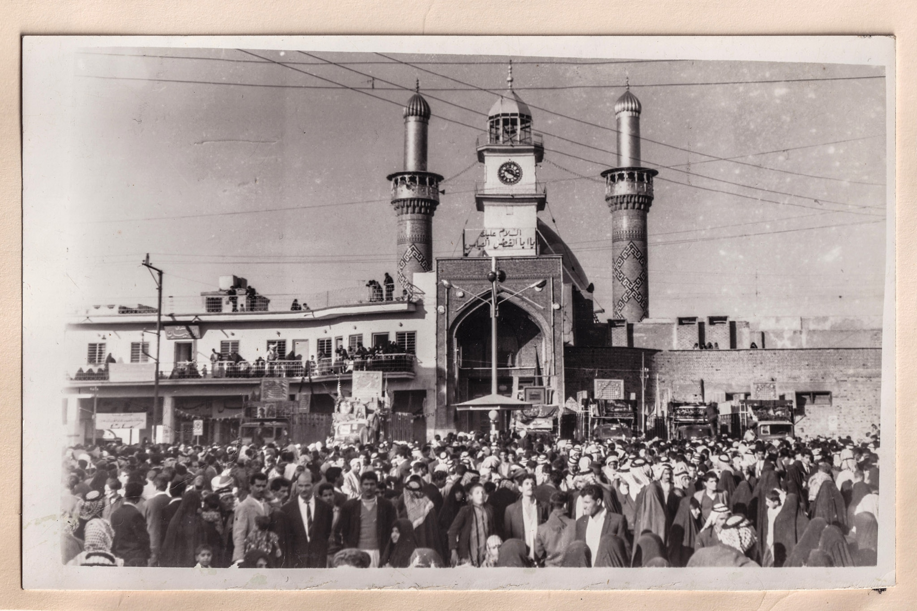A black and white photo of men standing in front of a shrine.
