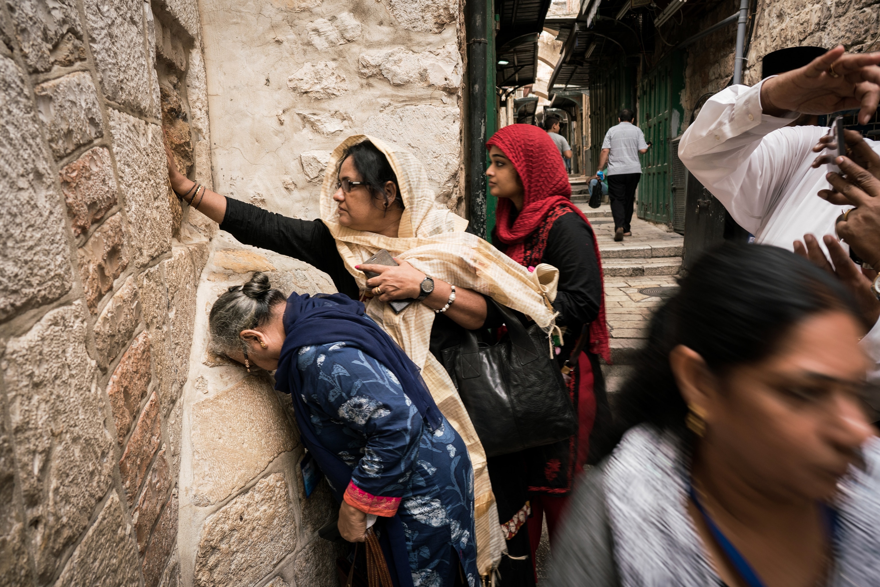 women touching the wall on the Via Dolorosa path in Jerusalem, Israel