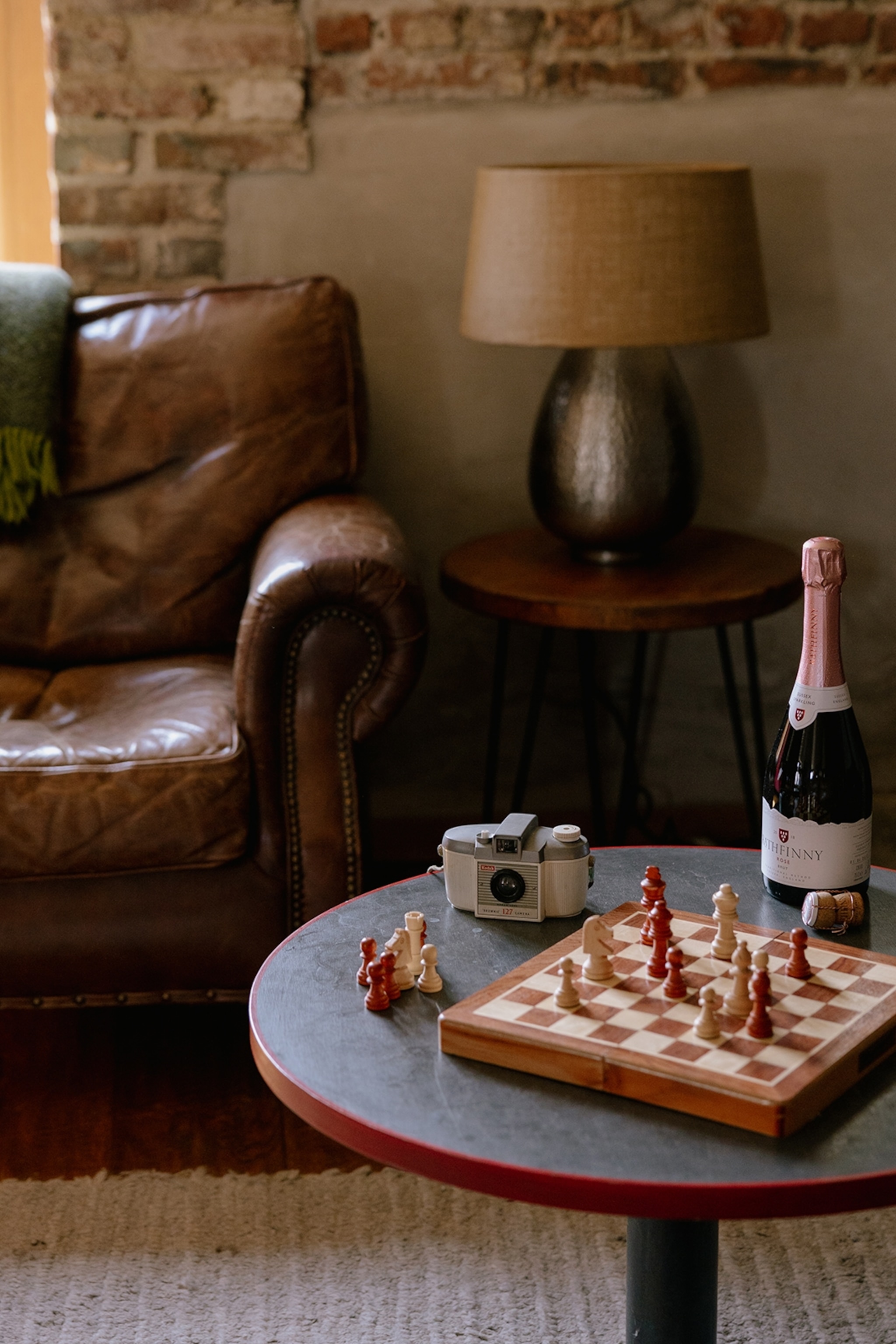 The cosy interiors of a barn hotel with leather sofas and a chess board on a side table.