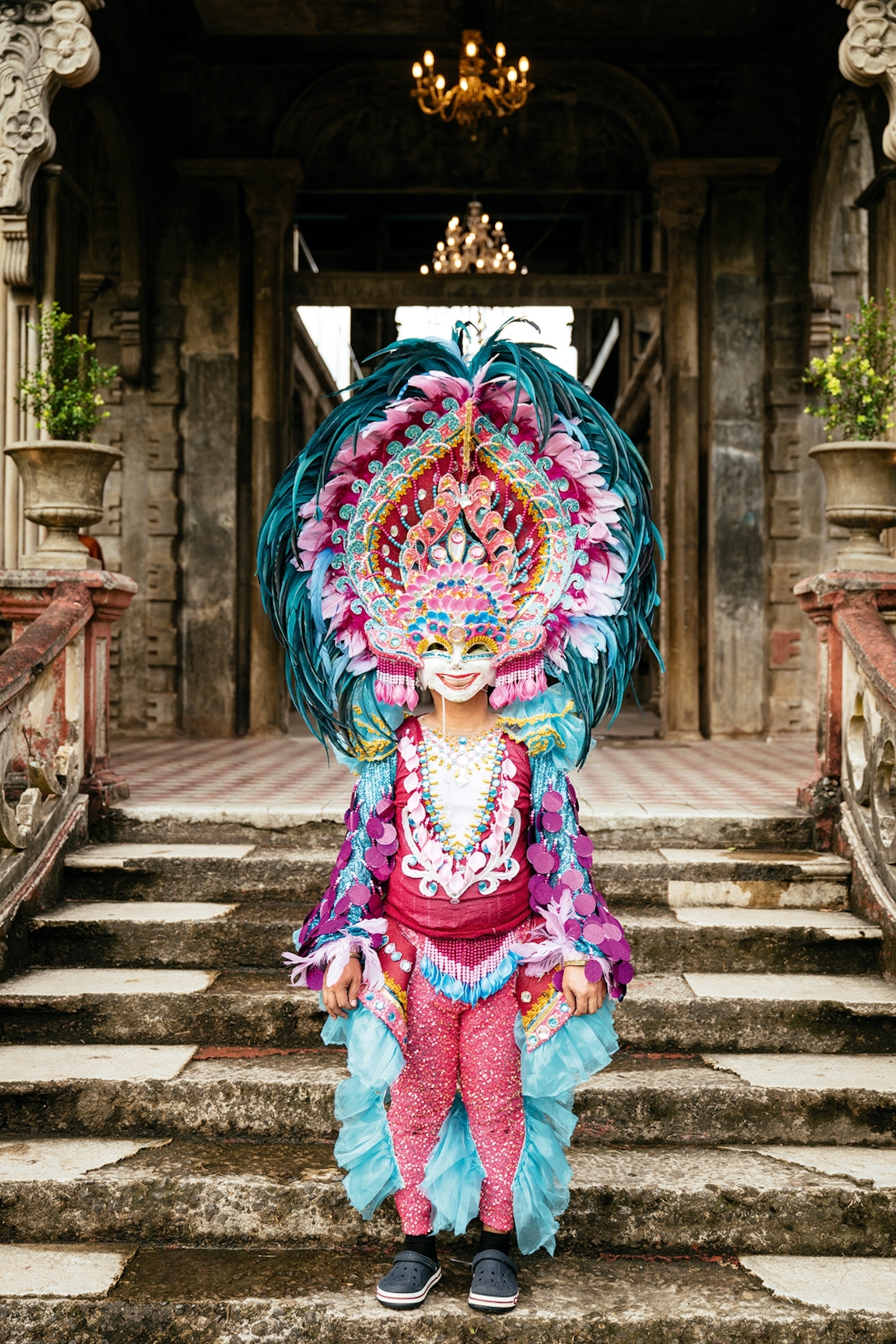 A visitor in traditional Filipino dress at the entrance of a mansion.