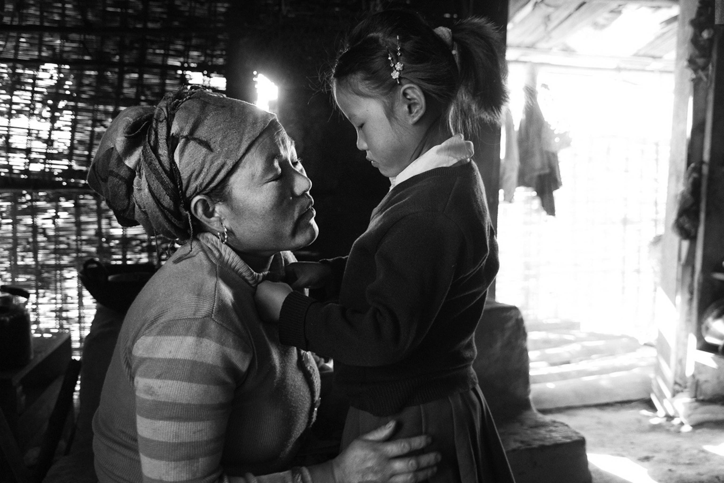 a mother looking at her daughter in her school uniform in their small home in Nepal, before she sets off for the school day