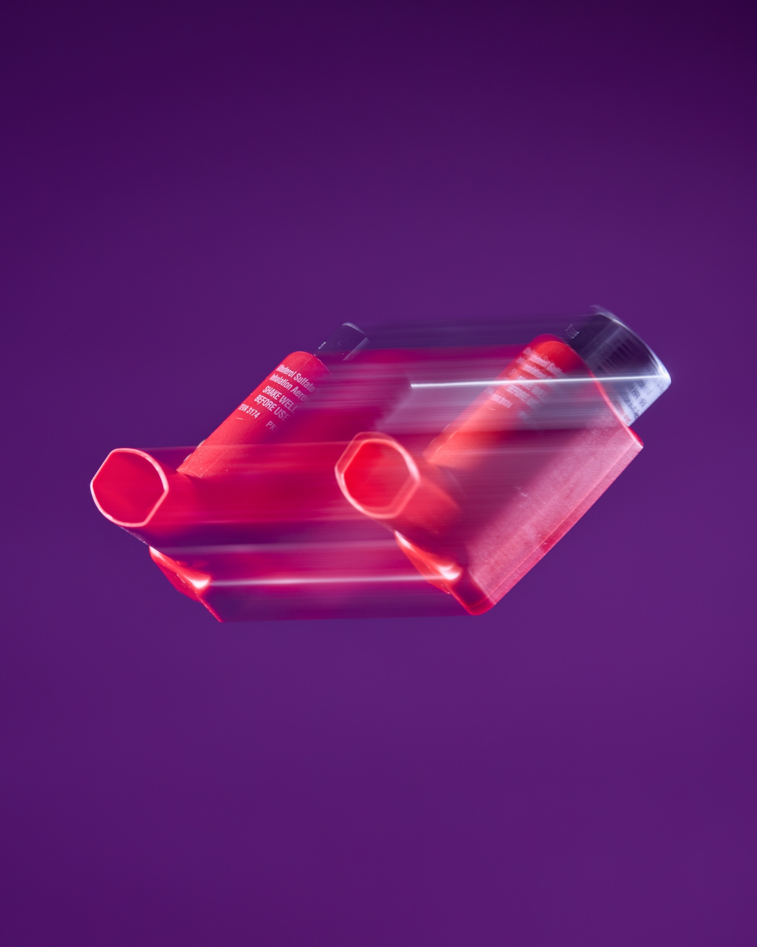 Red inhaler blurred on a purple background.